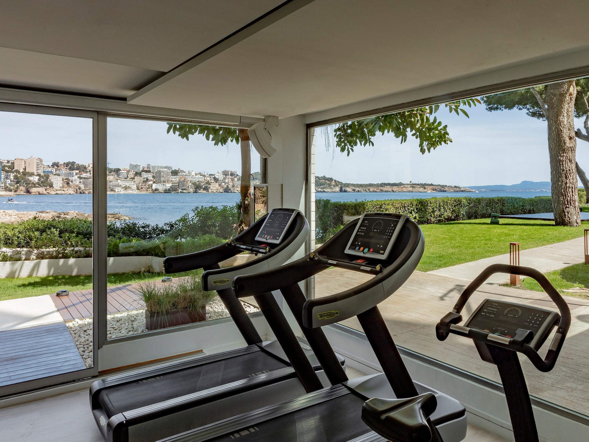 a gym with treadmills and a view of water and a city