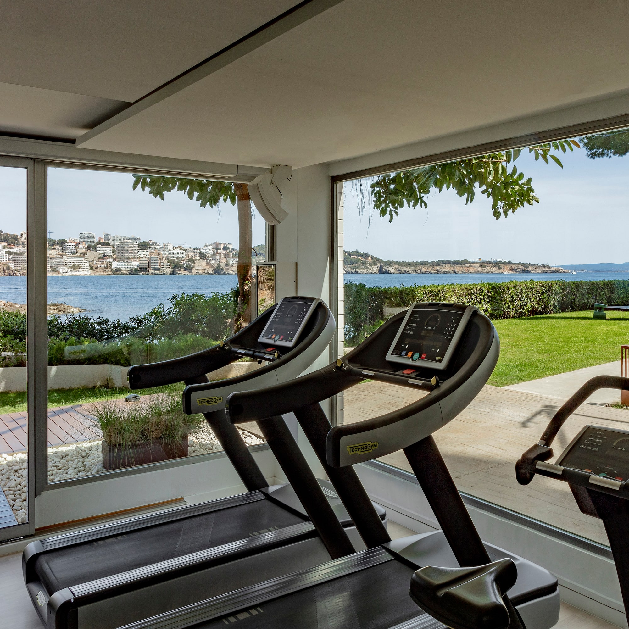 a gym with treadmills and a view of water and a city
