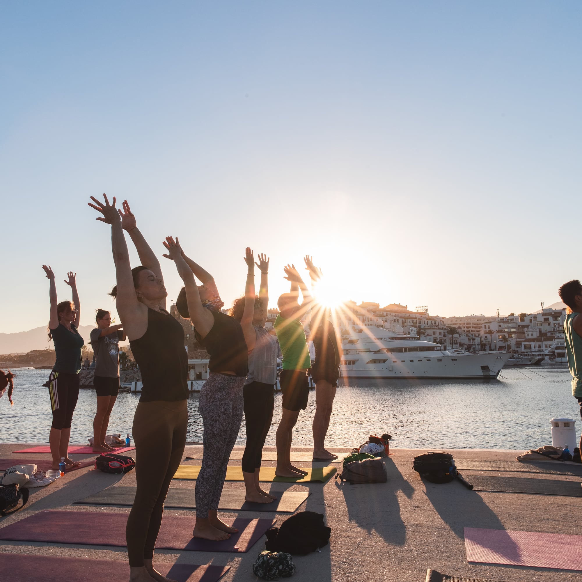 a group of people doing yoga on a dock with a boat in the background