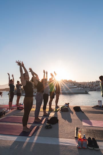 a group of people doing yoga on a dock with a boat in the background