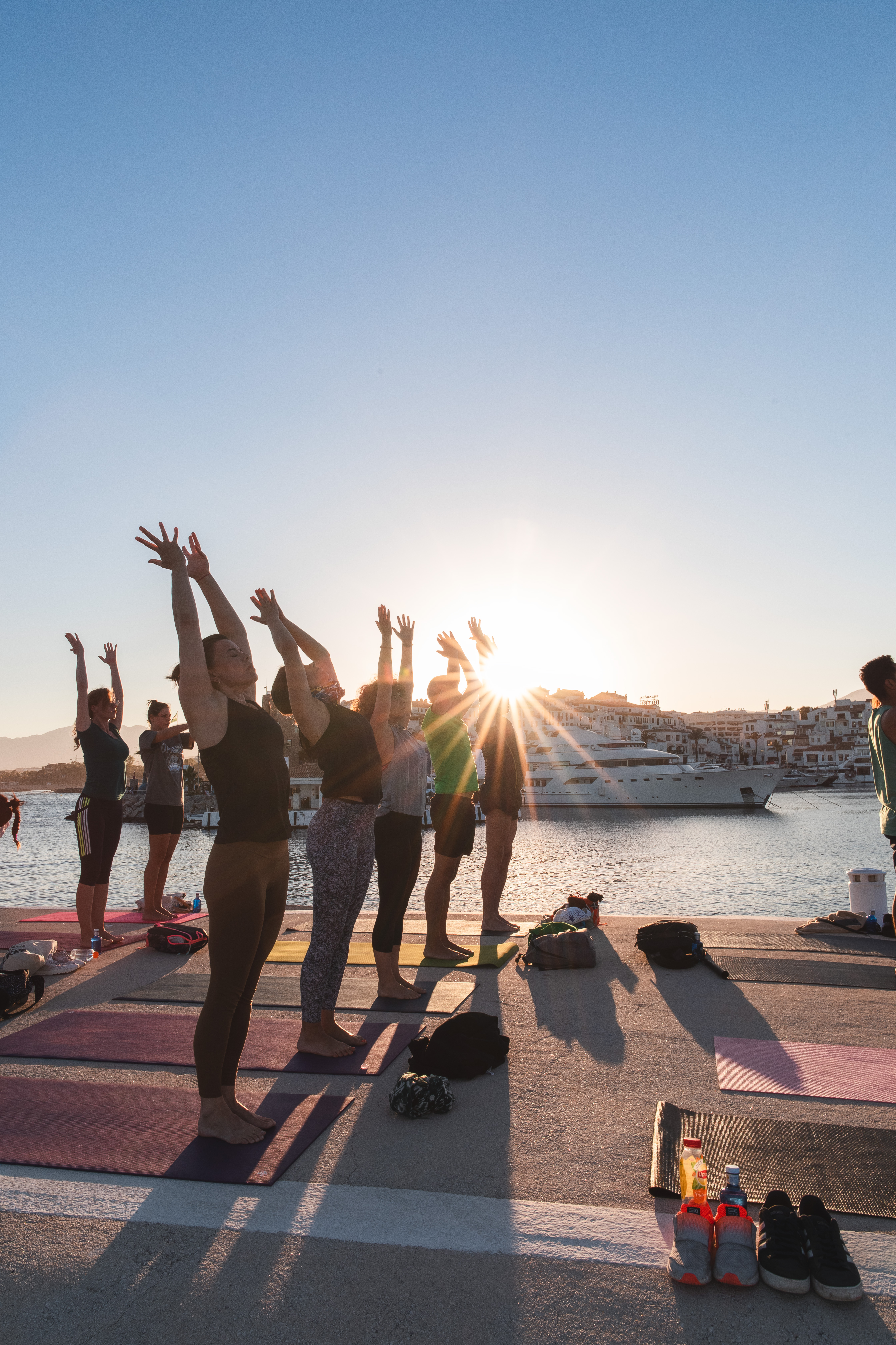 a group of people doing yoga on a dock with a boat in the background