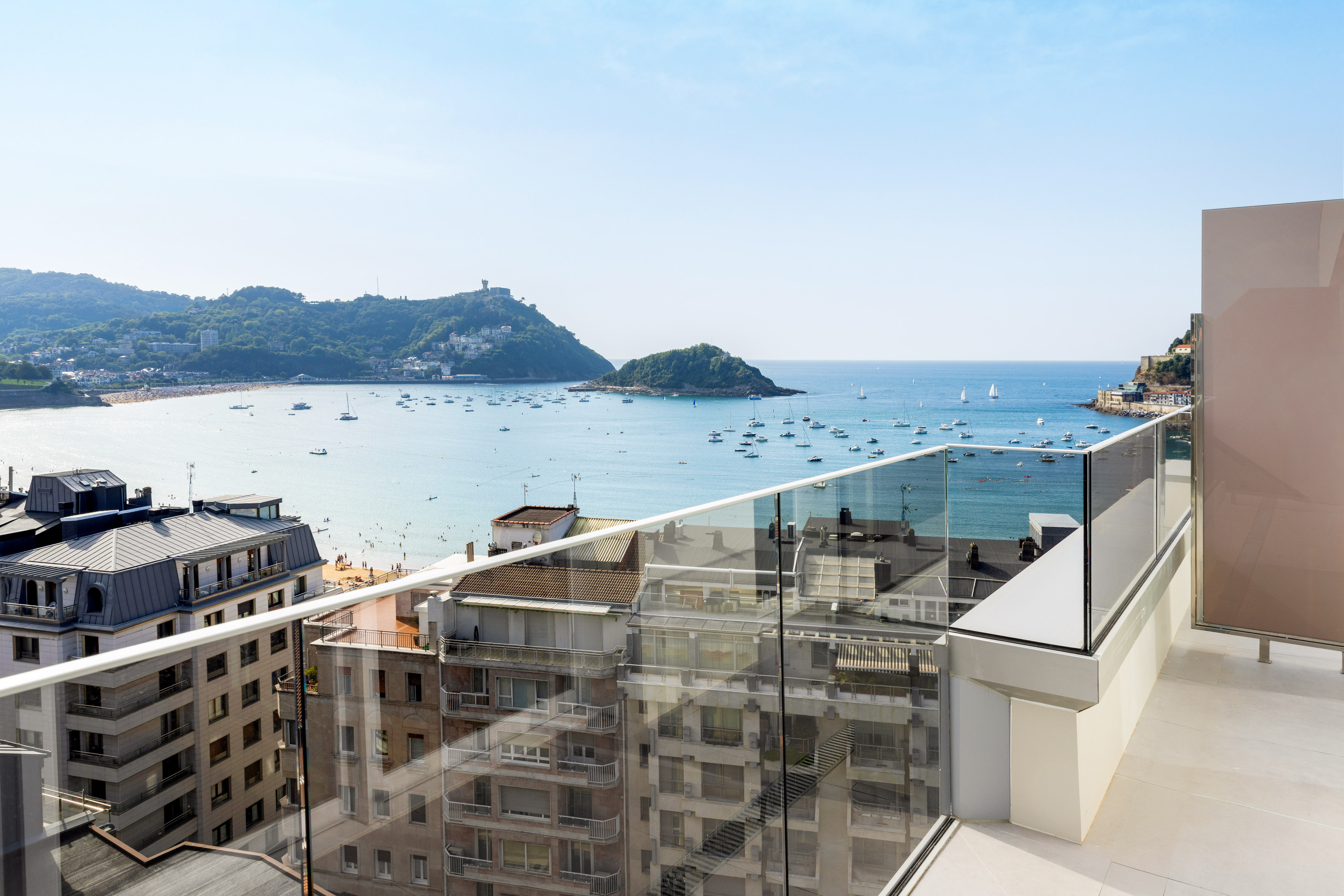 Bahía de La Concha, San Sebastián: barcos, playa y ciudad desde balcón.