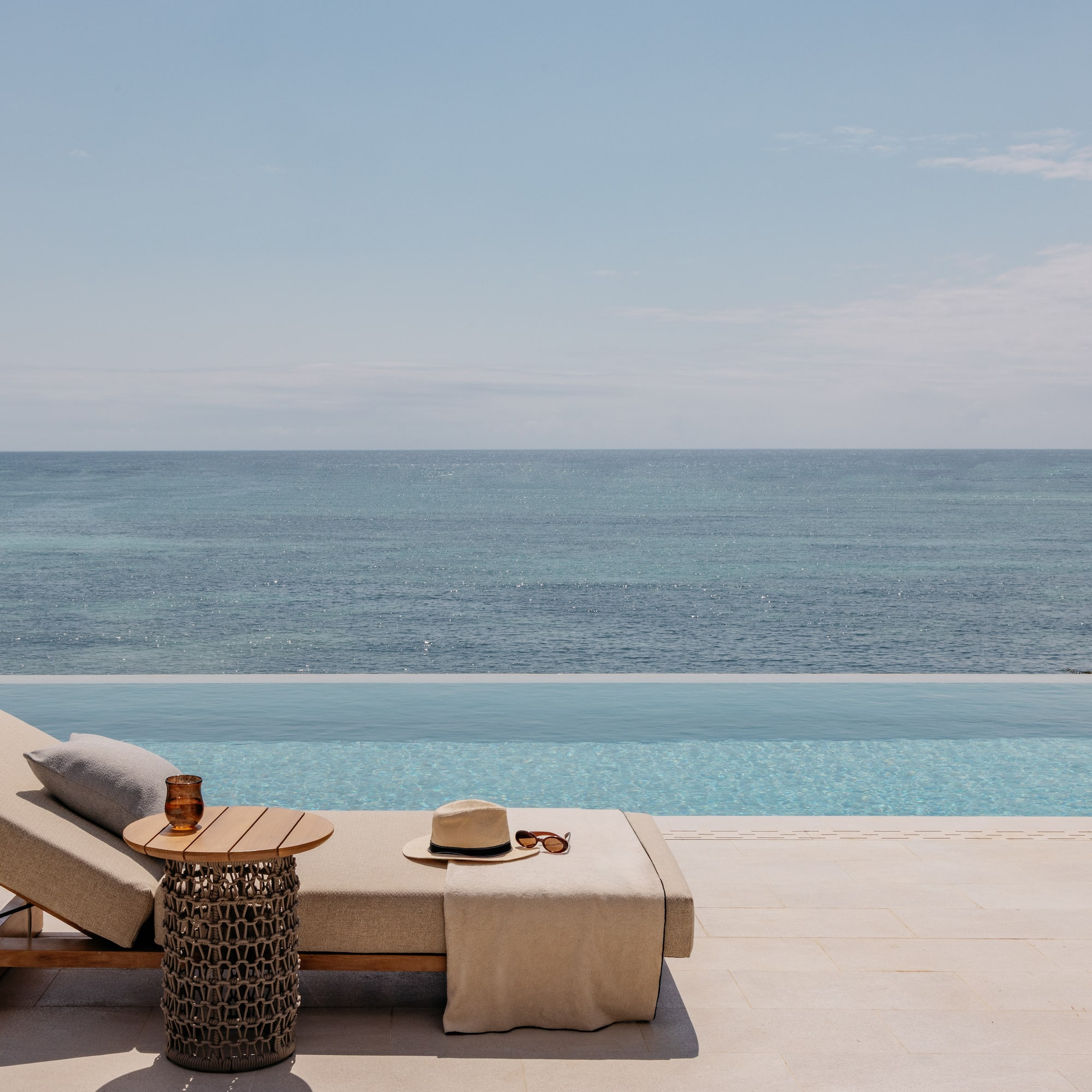 a lounge chair with a hat and sunglasses on it by a pool