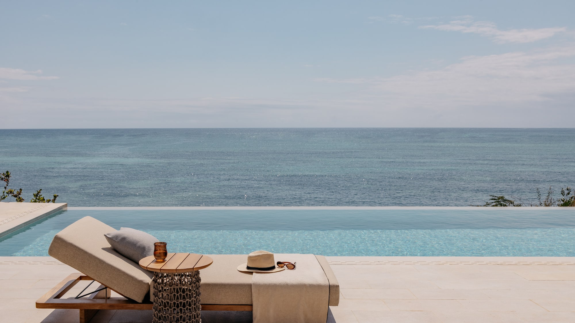 a lounge chair with a hat and sunglasses on it by a pool