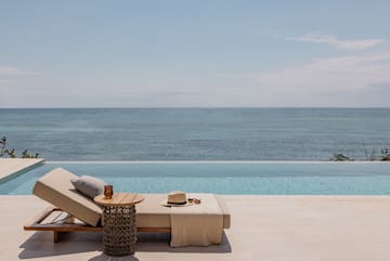 a lounge chair with a hat and sunglasses on it by a pool