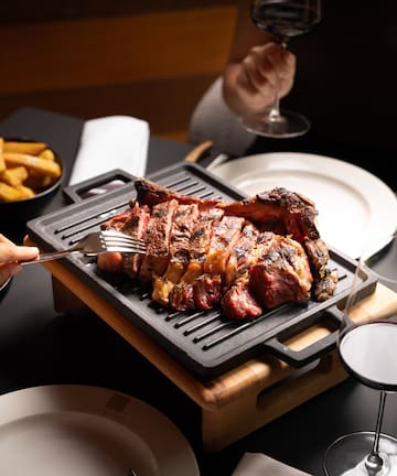 a group of people eating meat on a grill