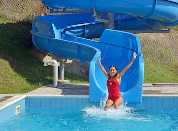 a woman in a red swimsuit in a pool with a water slide
