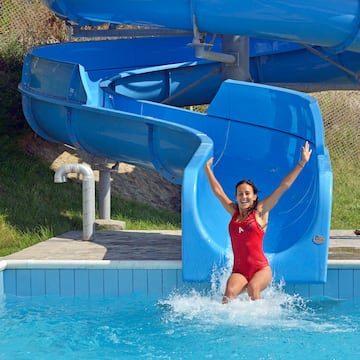 a woman in a red swimsuit in a pool with a water slide
