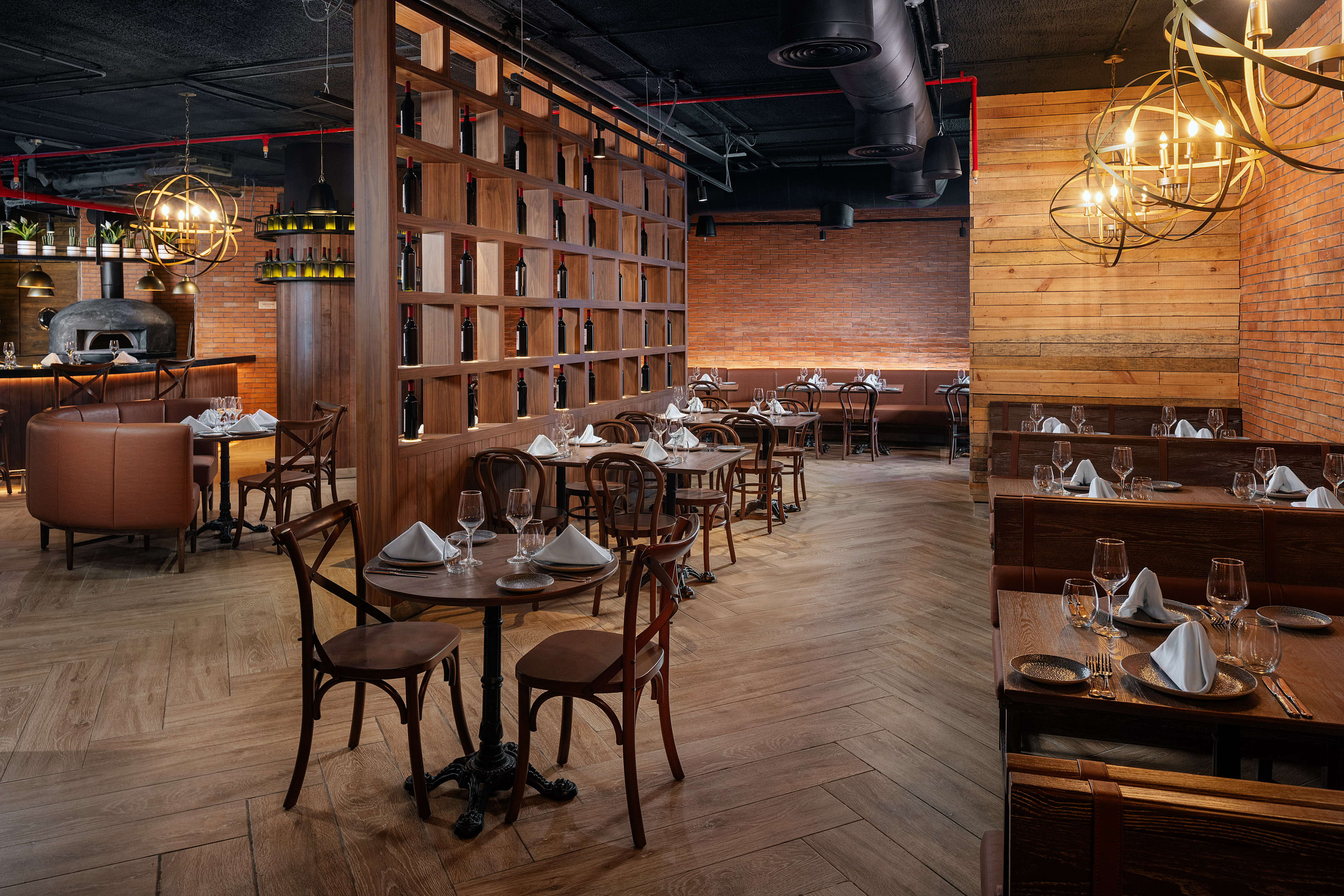 Elegant restaurant interior with wood wine display, brick walls, and a pizza oven.