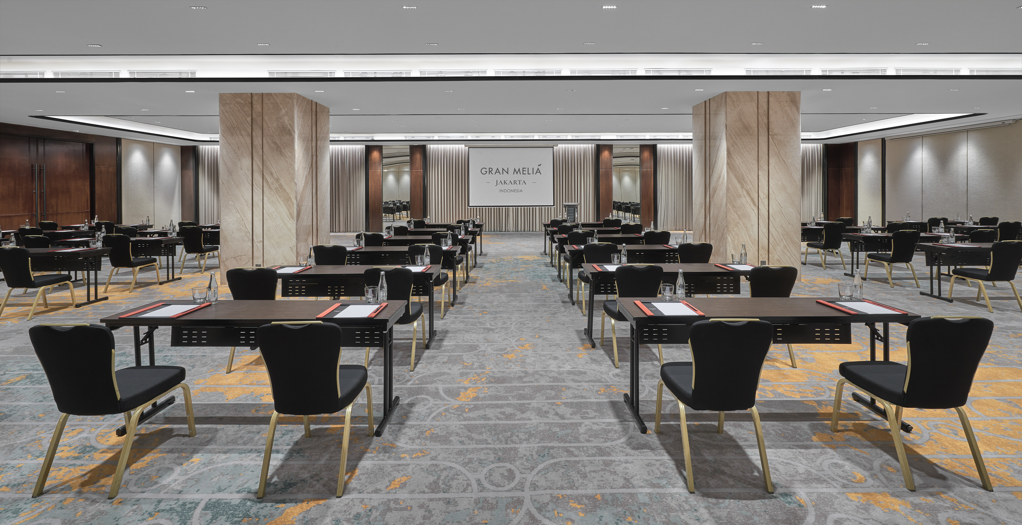 Gran Melia Jakarta large conference room with classroom setup, projector screen.