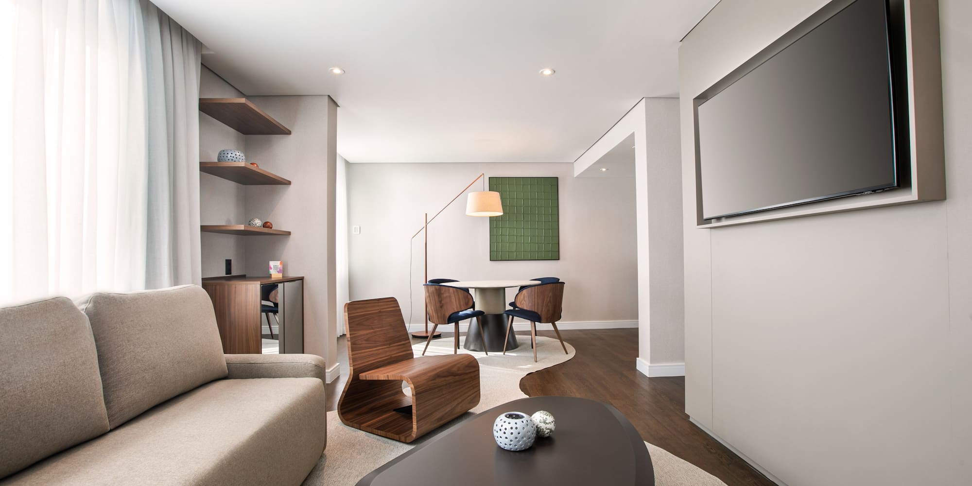 Spacious modern living room with sofa, coffee table, wall TV, and dining area.