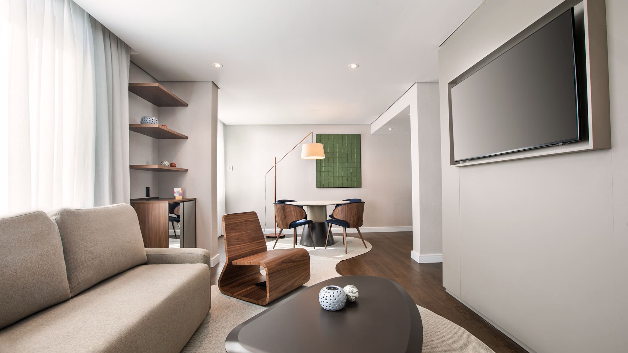 Spacious modern living room with sofa, coffee table, wall TV, and dining area.