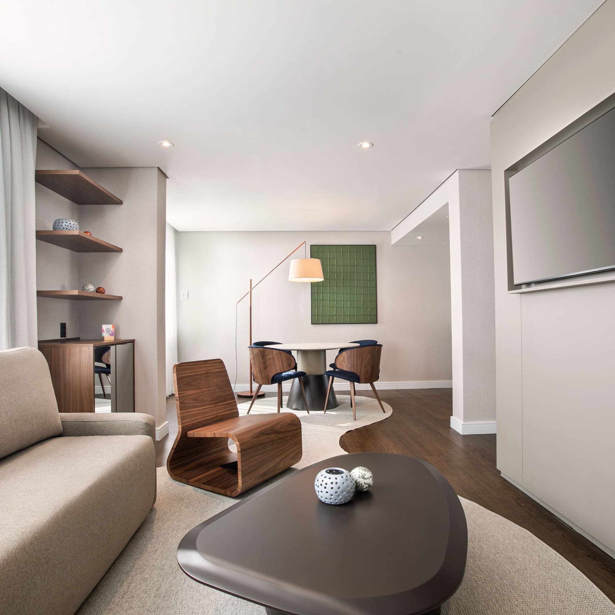 Spacious modern living room with sofa, coffee table, wall TV, and dining area.