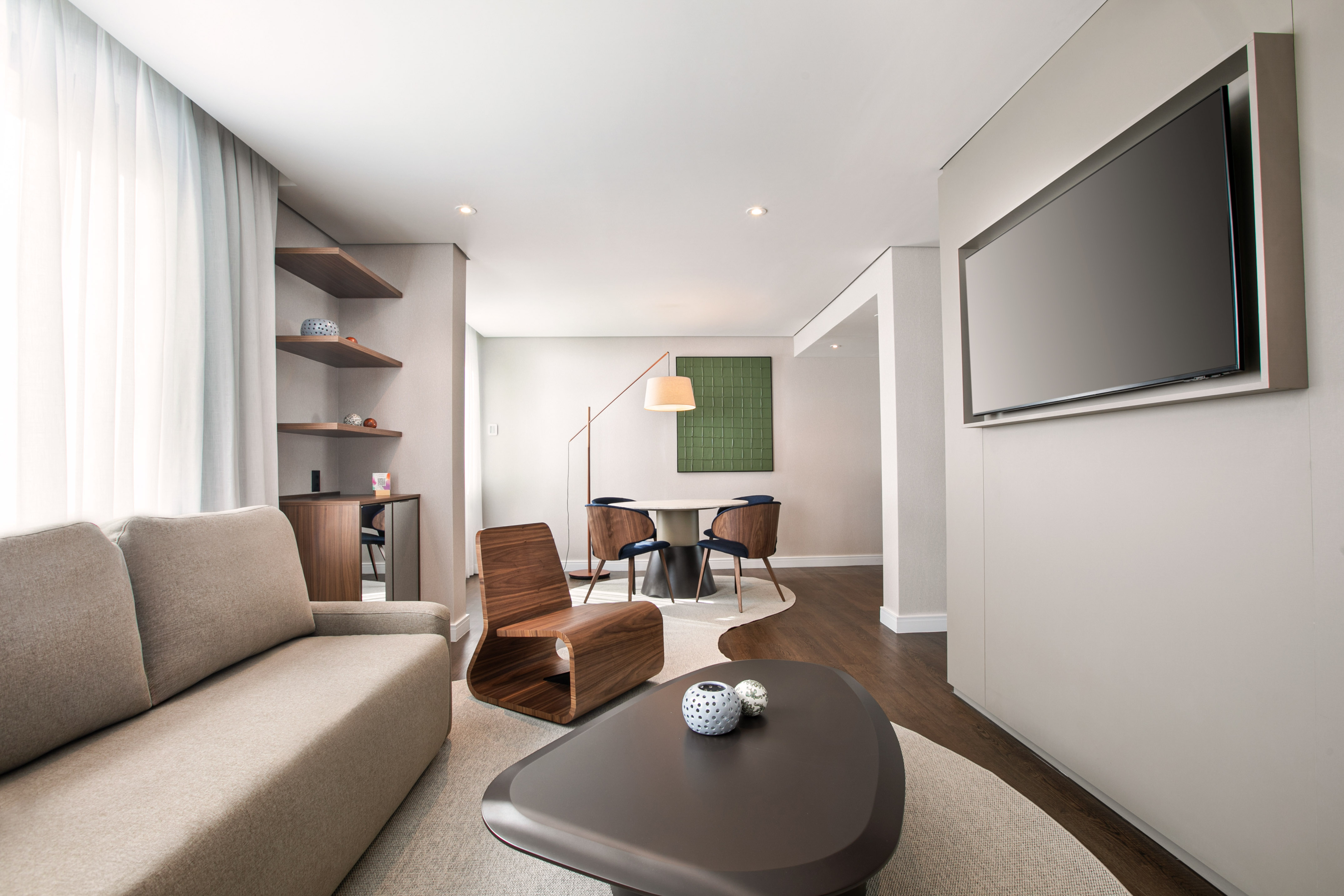 Spacious modern living room with sofa, coffee table, wall TV, and dining area.