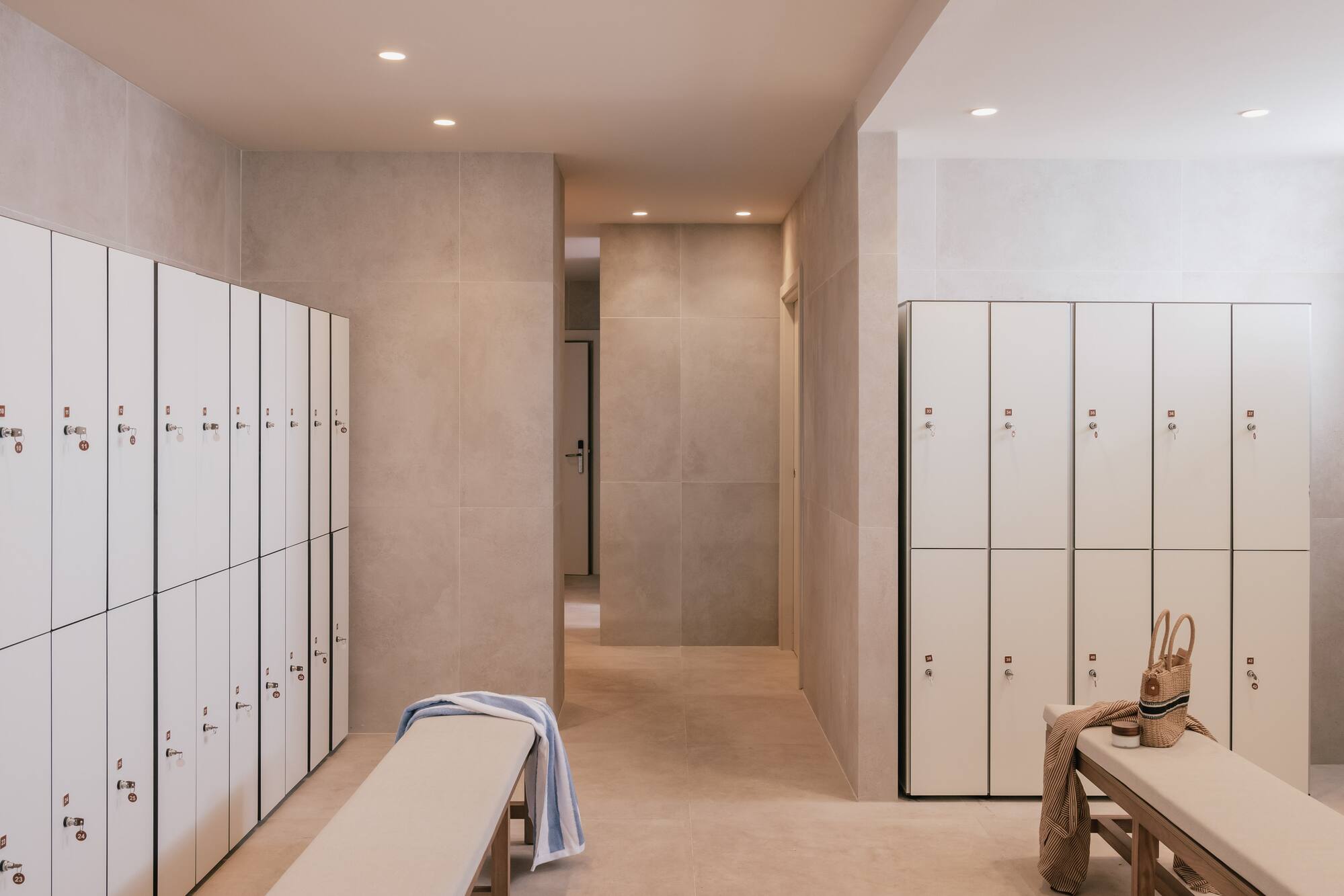 Modern spa changing room with white lockers, benches, and clean tiled interior.