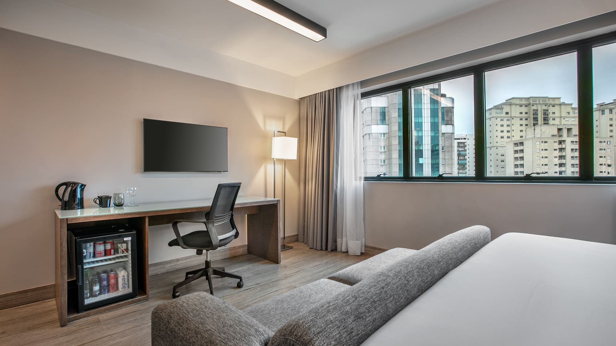 Quarto de hotel moderno com escrivaninha, TV e vista para a cidade. - Deluxe Room Queen - Meliá Ibirapuera, São Paulo