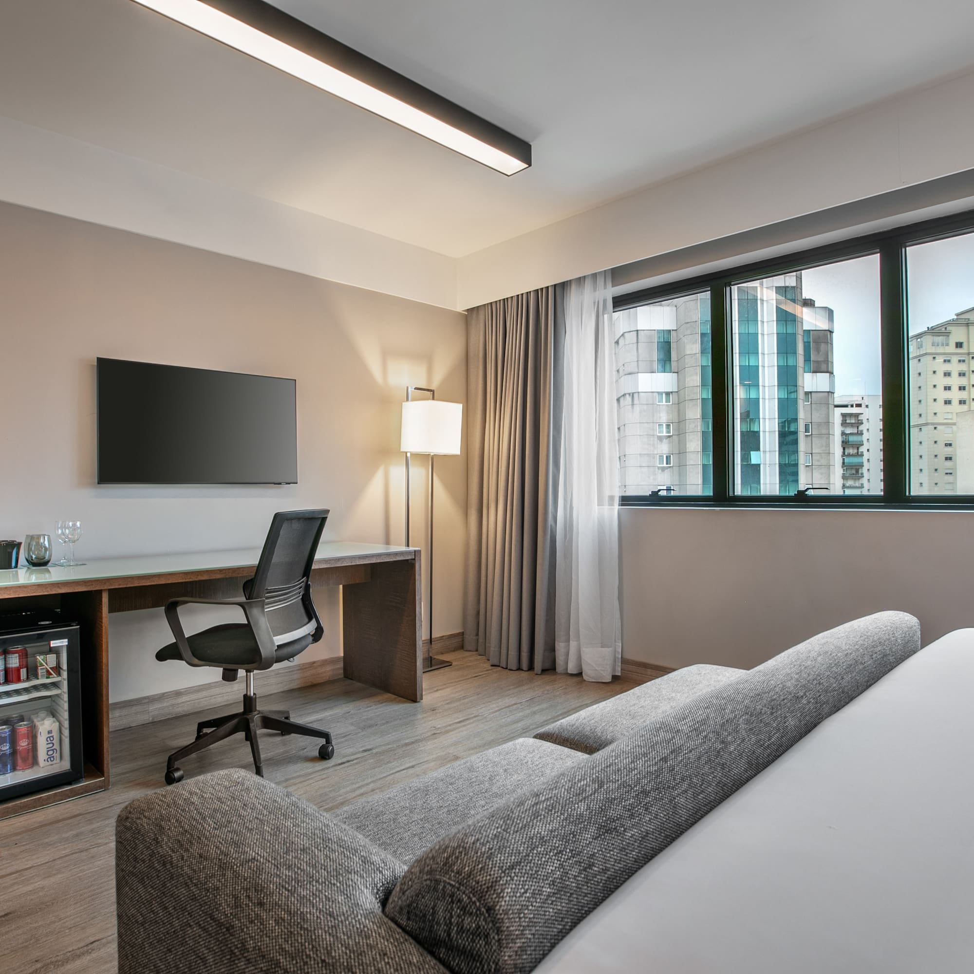 Quarto de hotel moderno com escrivaninha, TV e vista para a cidade. - Deluxe Room Queen - Meliá Ibirapuera, São Paulo