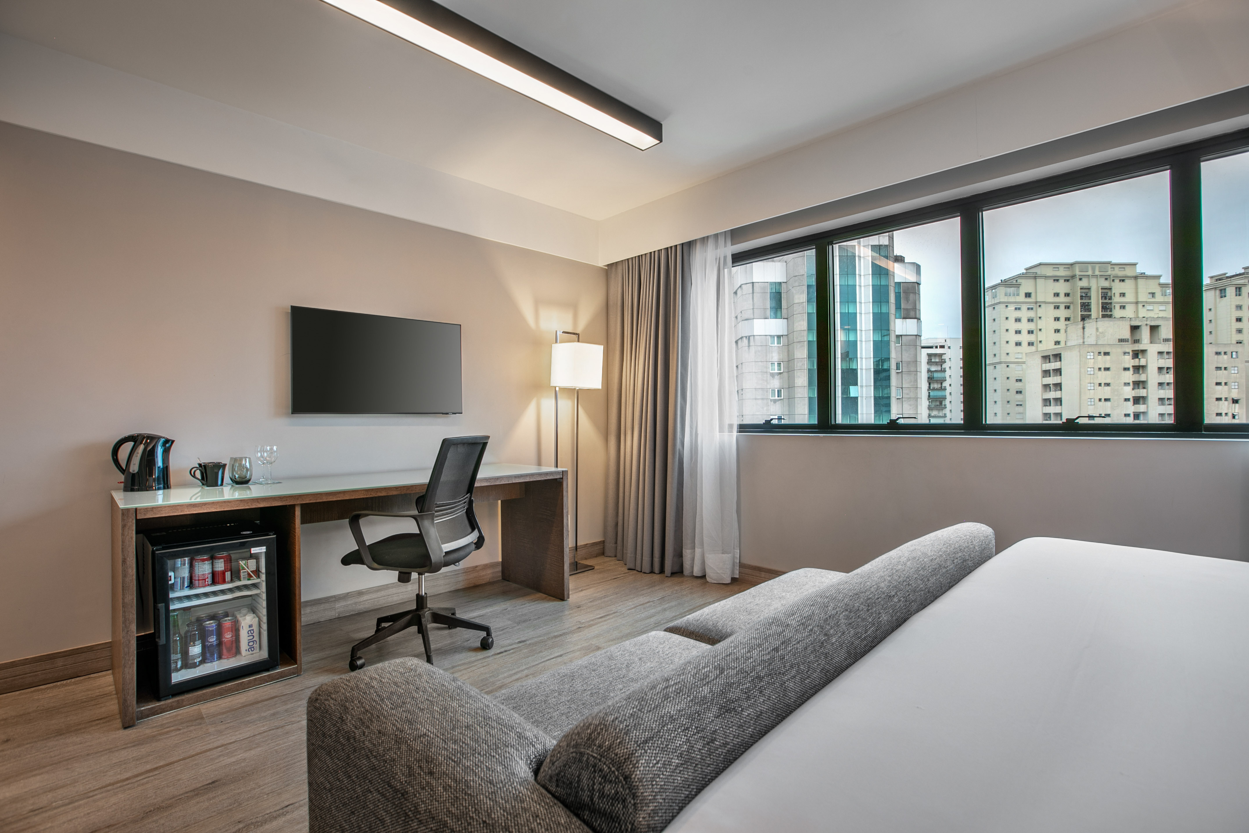 Quarto de hotel moderno com escrivaninha, TV e vista para a cidade. - Deluxe Room Queen - Meliá Ibirapuera, São Paulo