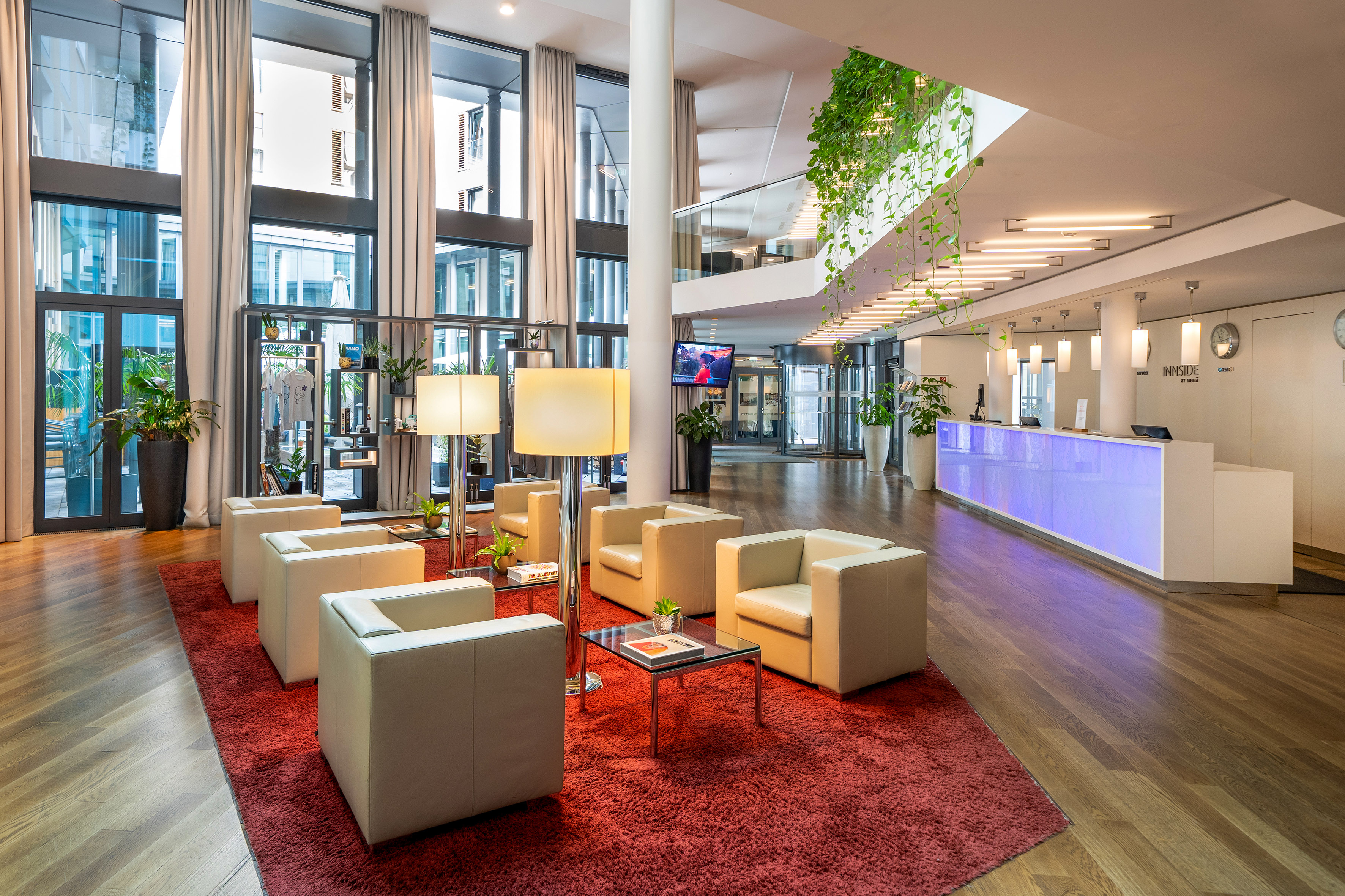 Hotel lobby with modern lounge seating, bright reception desk, and large windows.