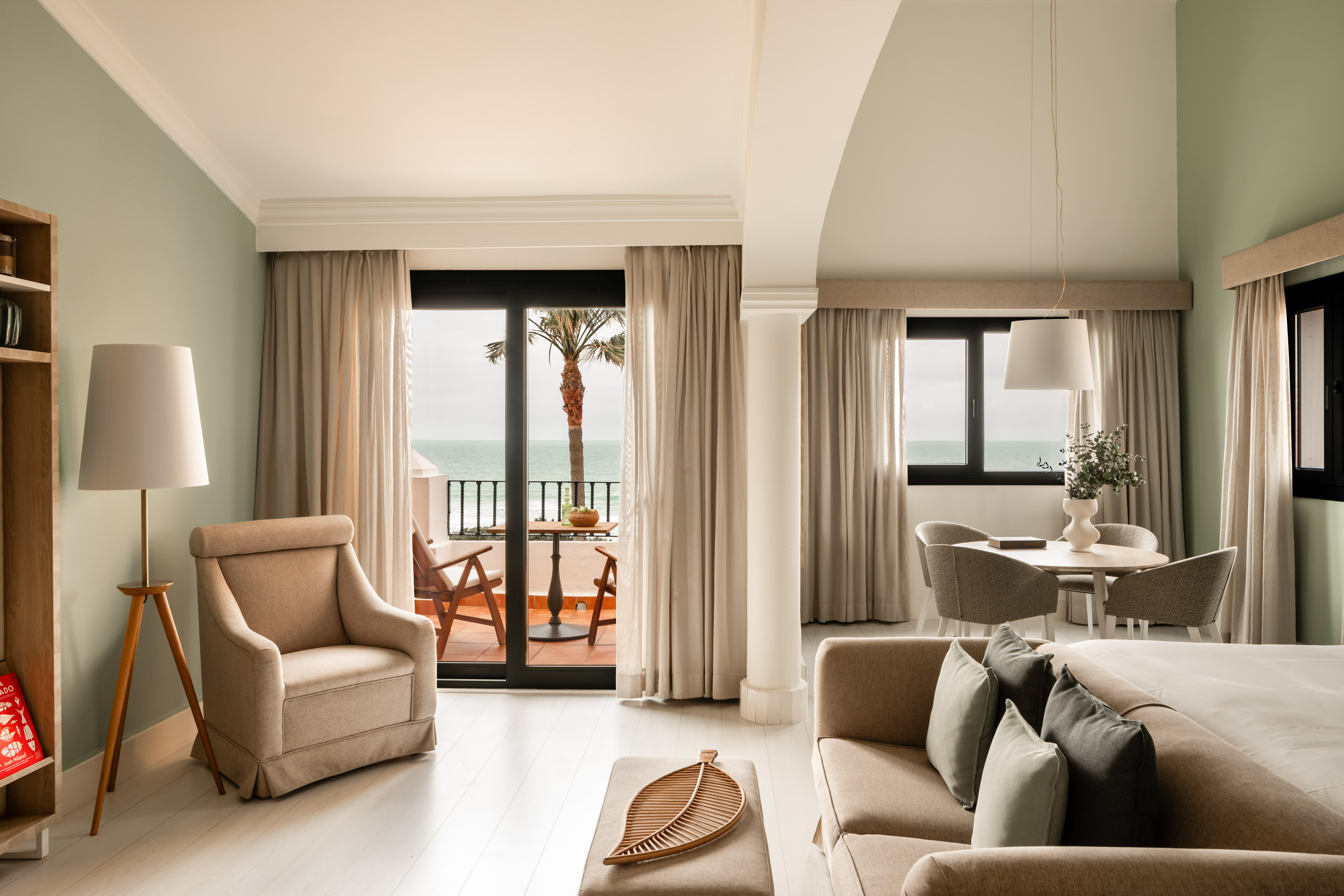 Modern oceanfront hotel suite with balcony, living area, and dining space.