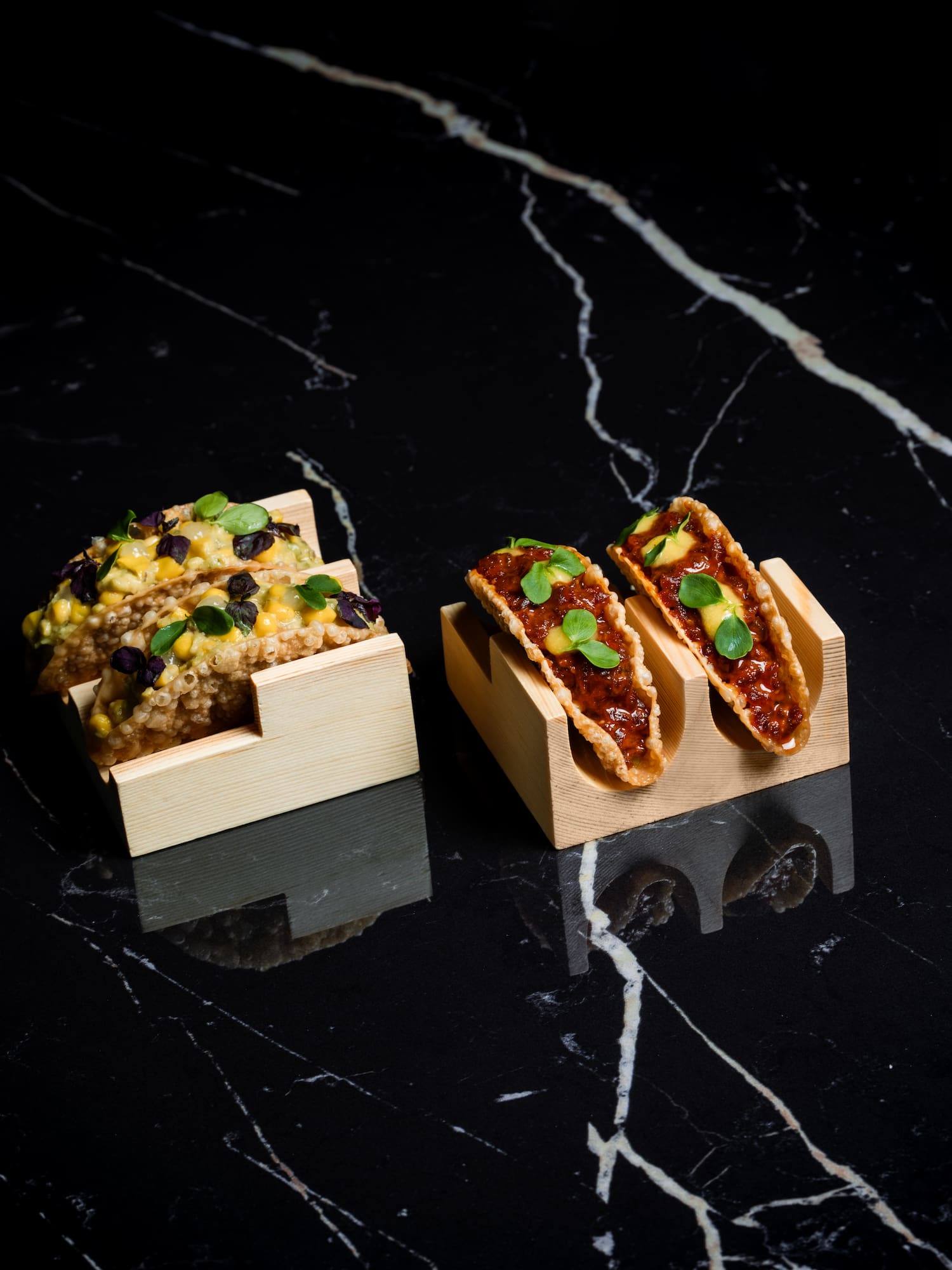 tacos in wooden holders on a black counter