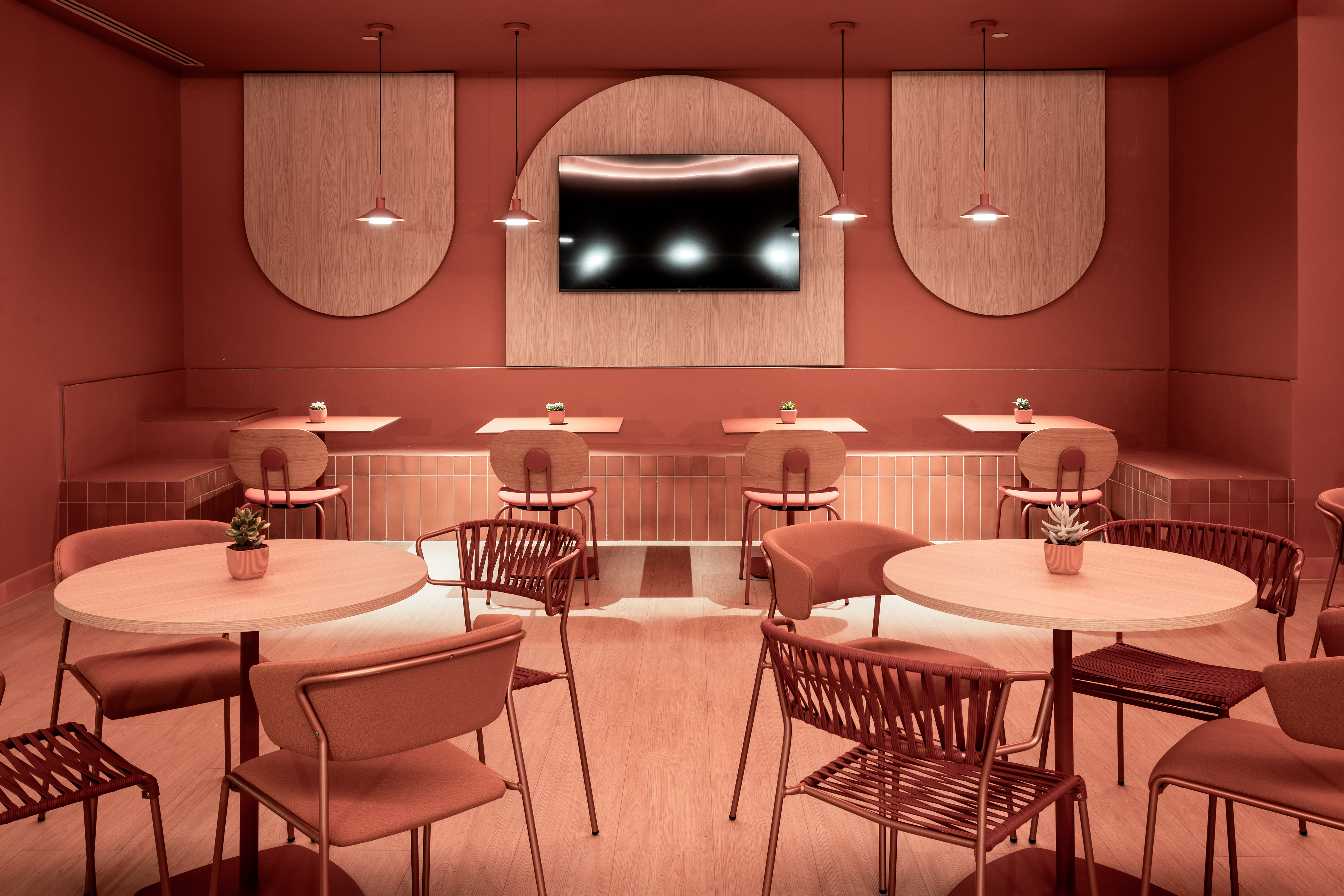 Modern cafe interior with terracotta walls, wooden tables, booth seating.