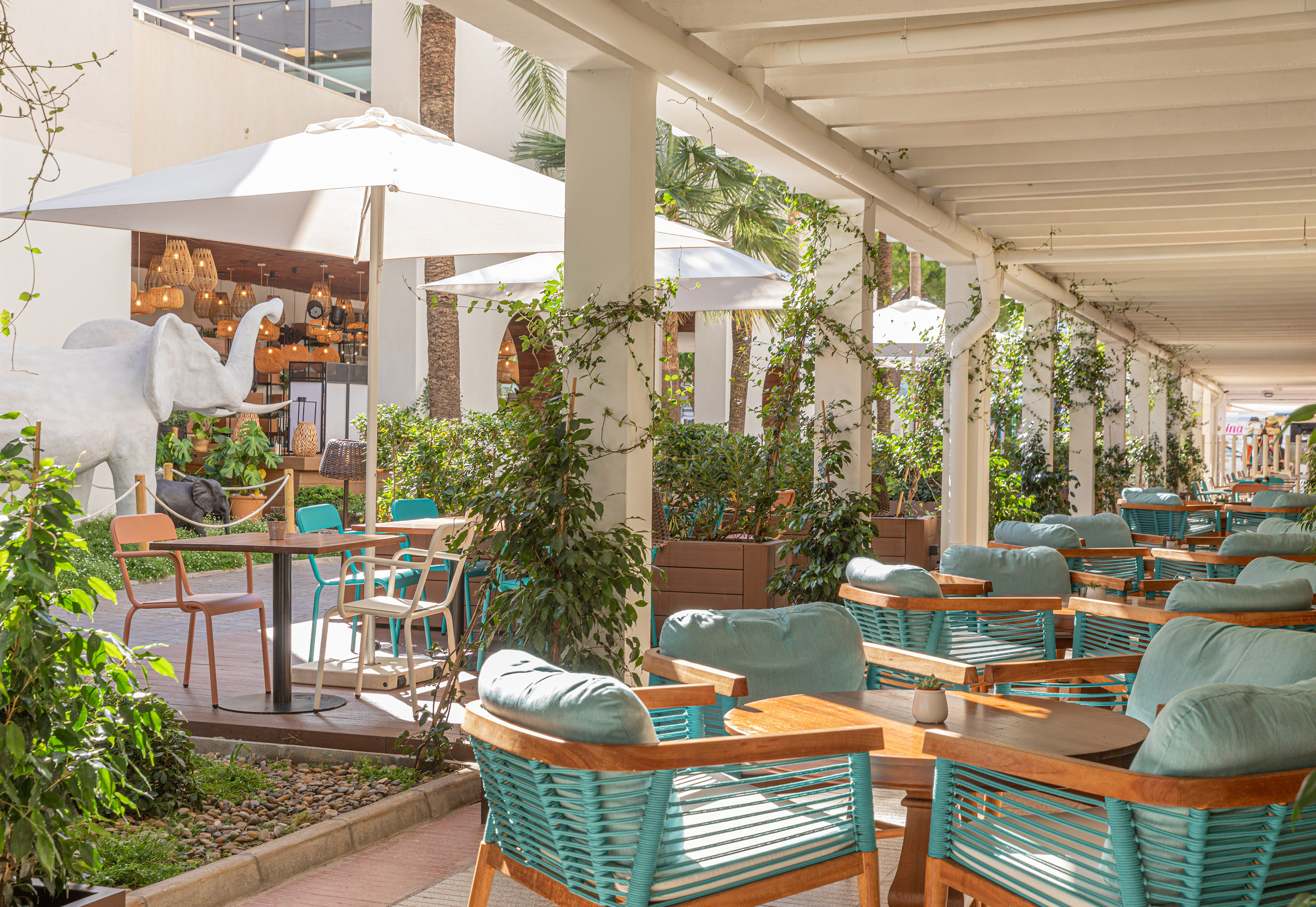 Tropical outdoor patio with white elephant statue and teal seating.