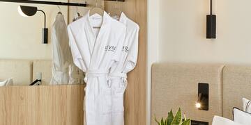 a room with white bathrobes and a plant
