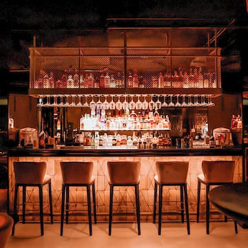 a bar with many glasses and a shelf above it