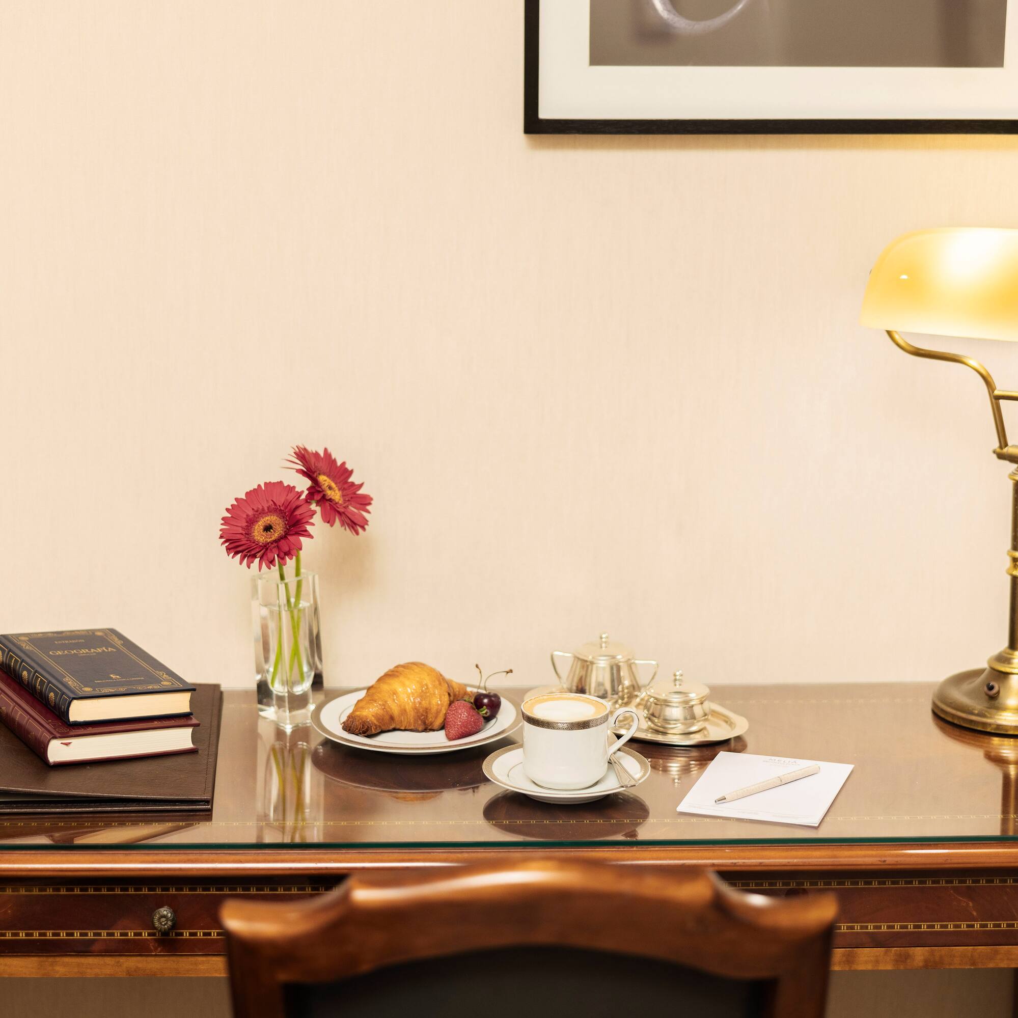a desk with a lamp and a plate of food and a book