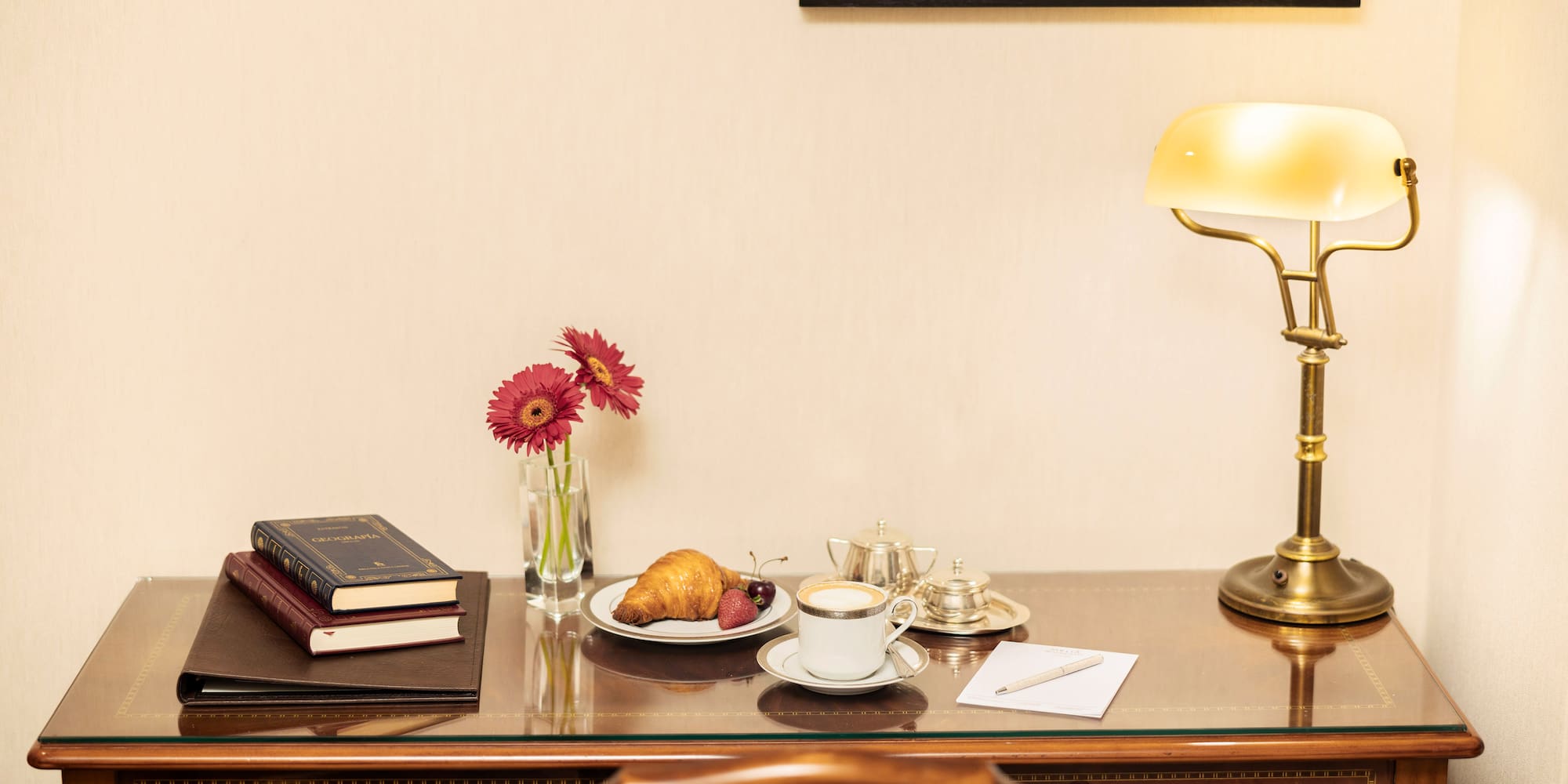 a desk with a lamp and a plate of food and a book