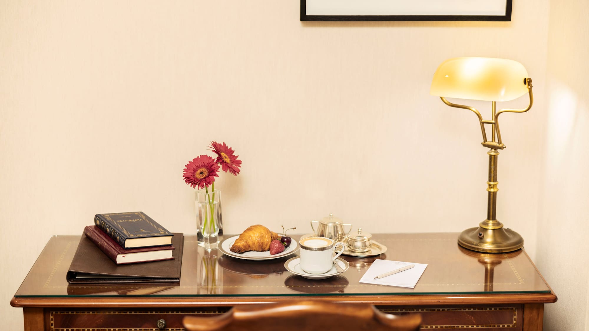 a desk with a lamp and a plate of food and a book