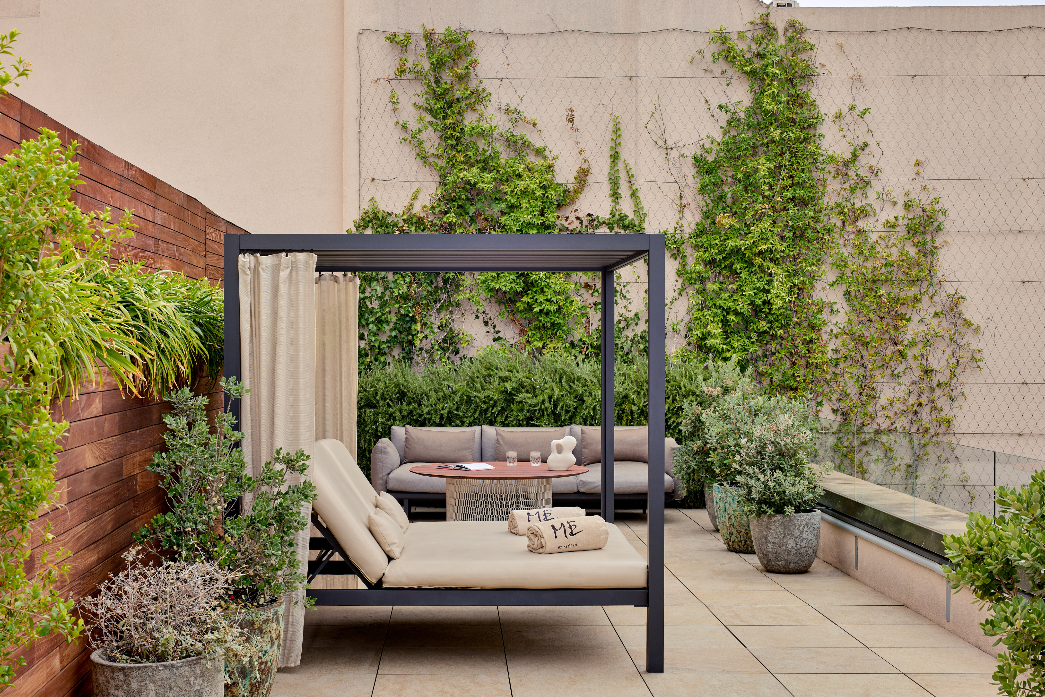 Luxury rooftop terrace with canopy daybed, outdoor sofa, and green wall.