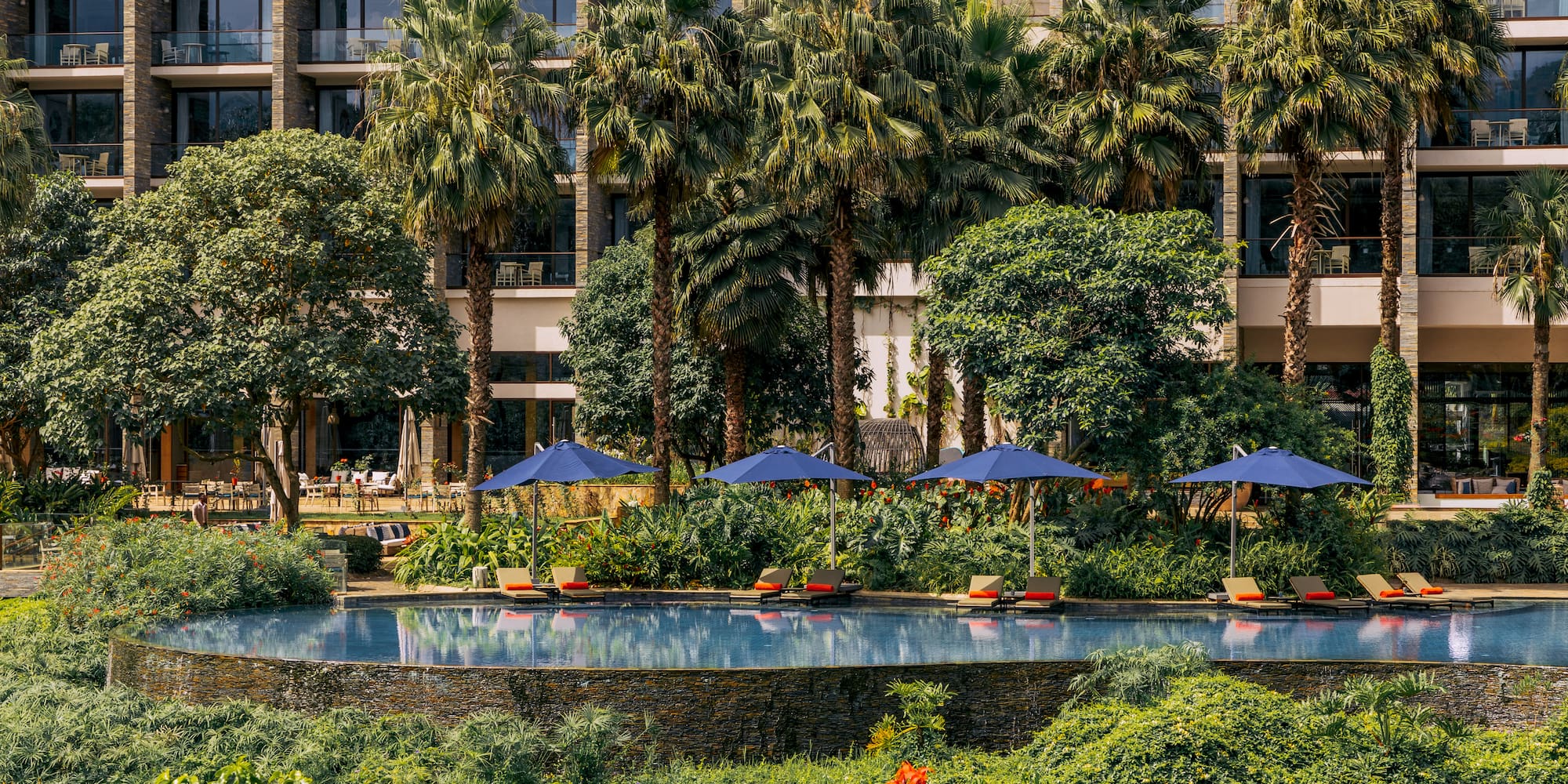 a pool with umbrellas and chairs in front of a building