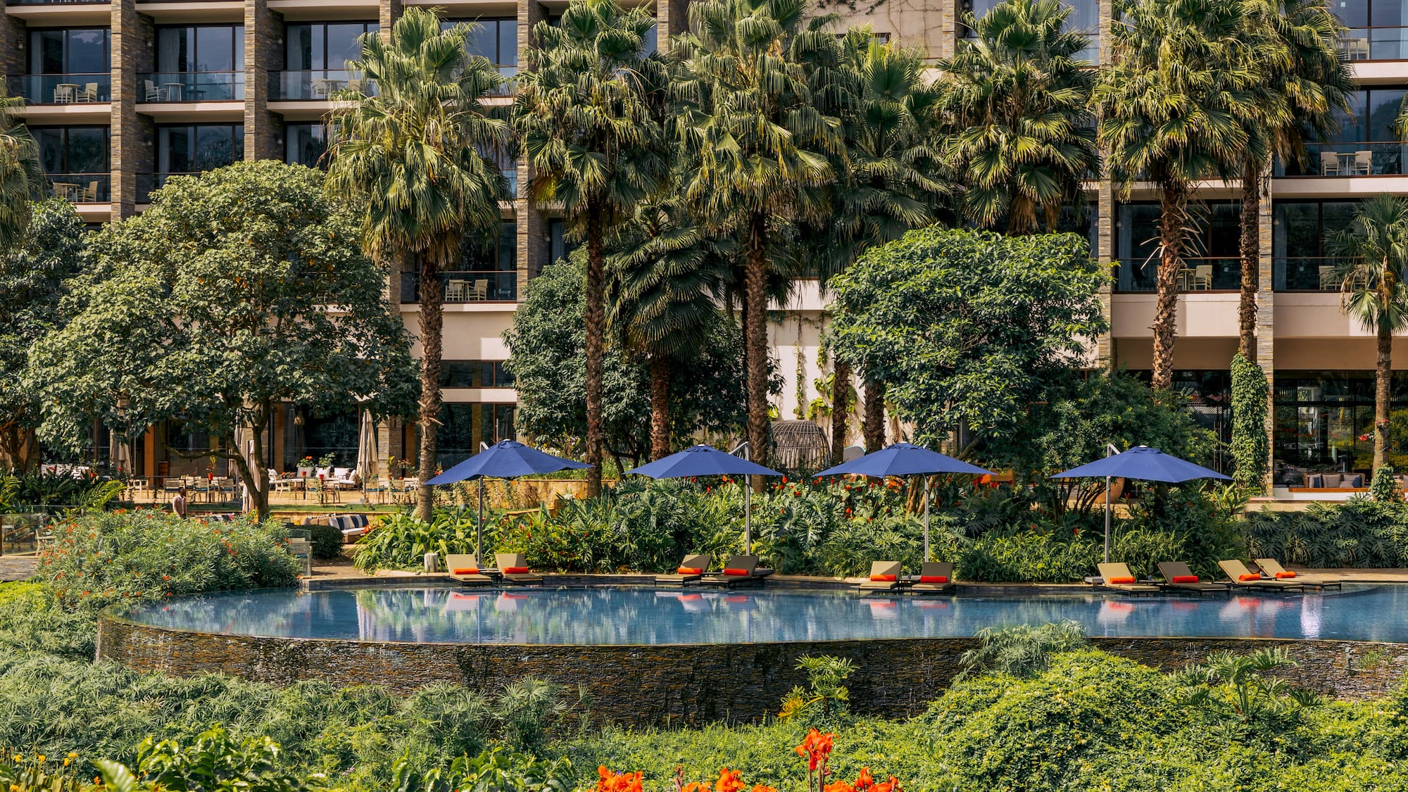 a pool with umbrellas and chairs in front of a building