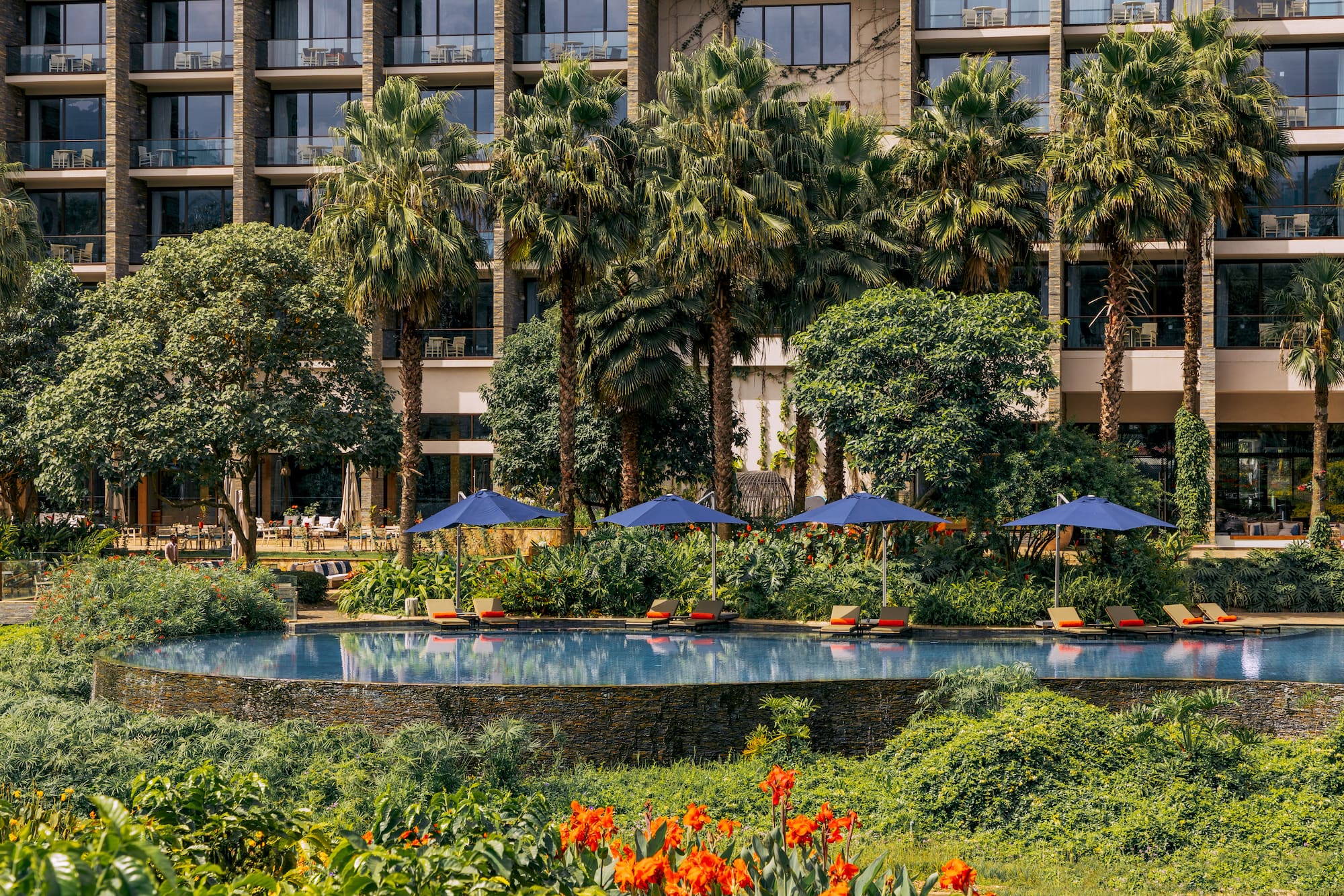 a pool with umbrellas and chairs in front of a building