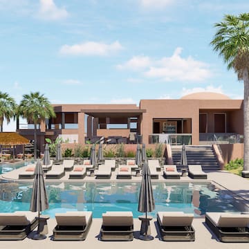 a pool with lounge chairs and umbrellas in front of a building