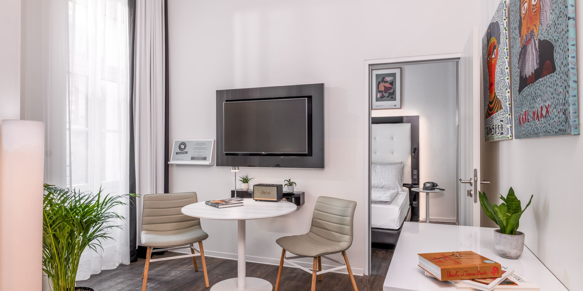 Stylish hotel room with contemporary decor, TV, small table, and bedroom access.