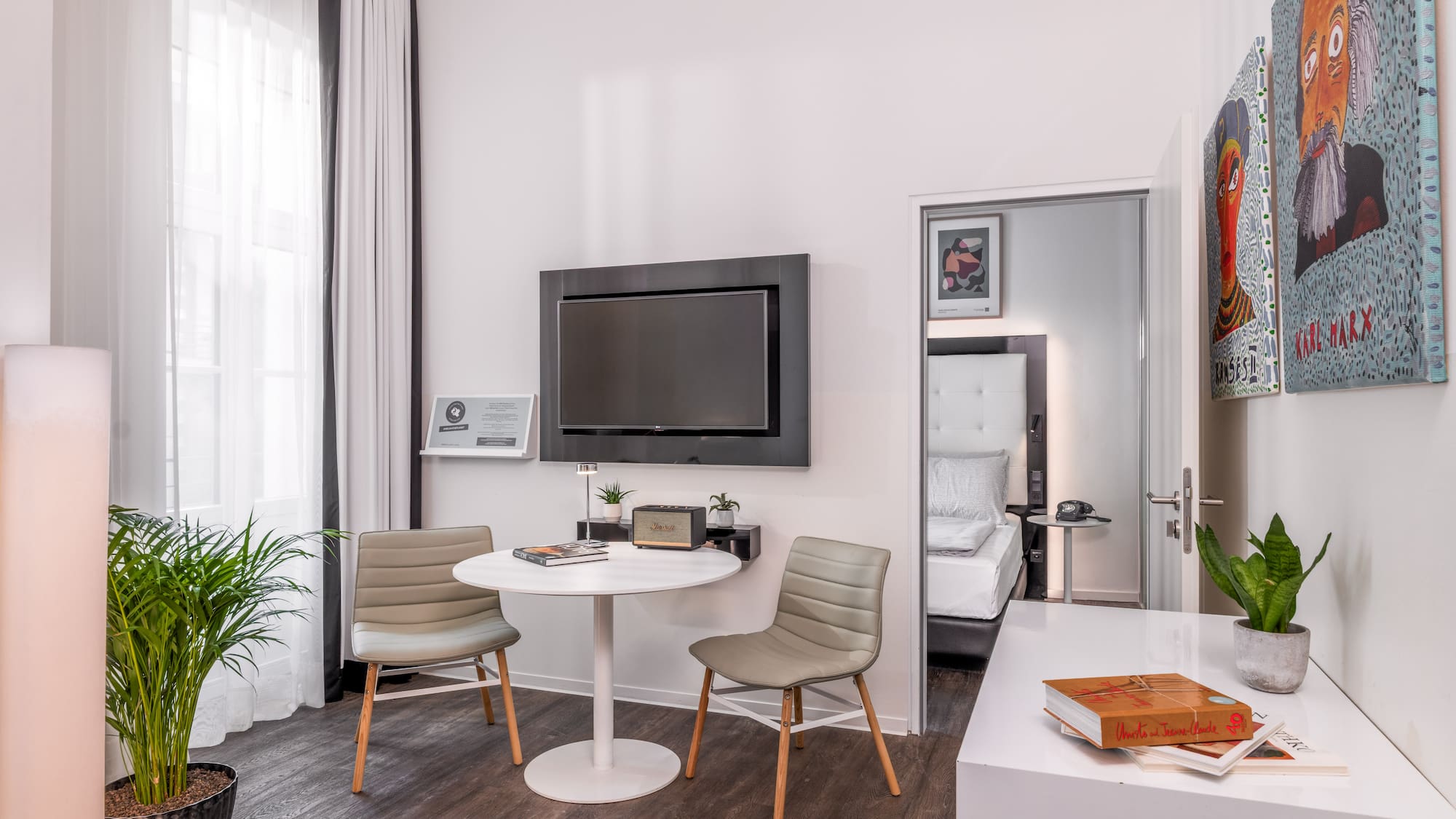 Stylish hotel room with contemporary decor, TV, small table, and bedroom access.