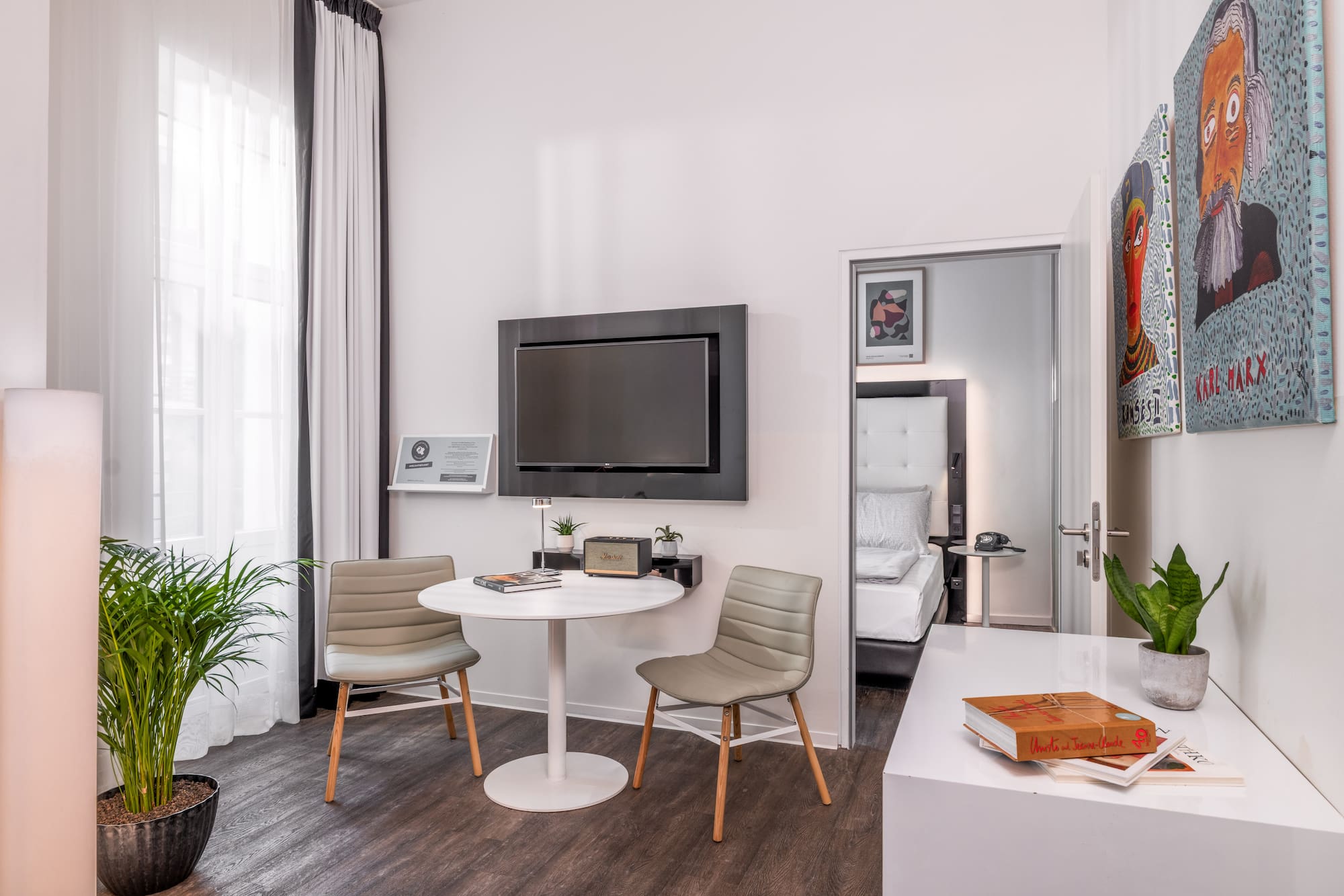 Stylish hotel room with contemporary decor, TV, small table, and bedroom access.