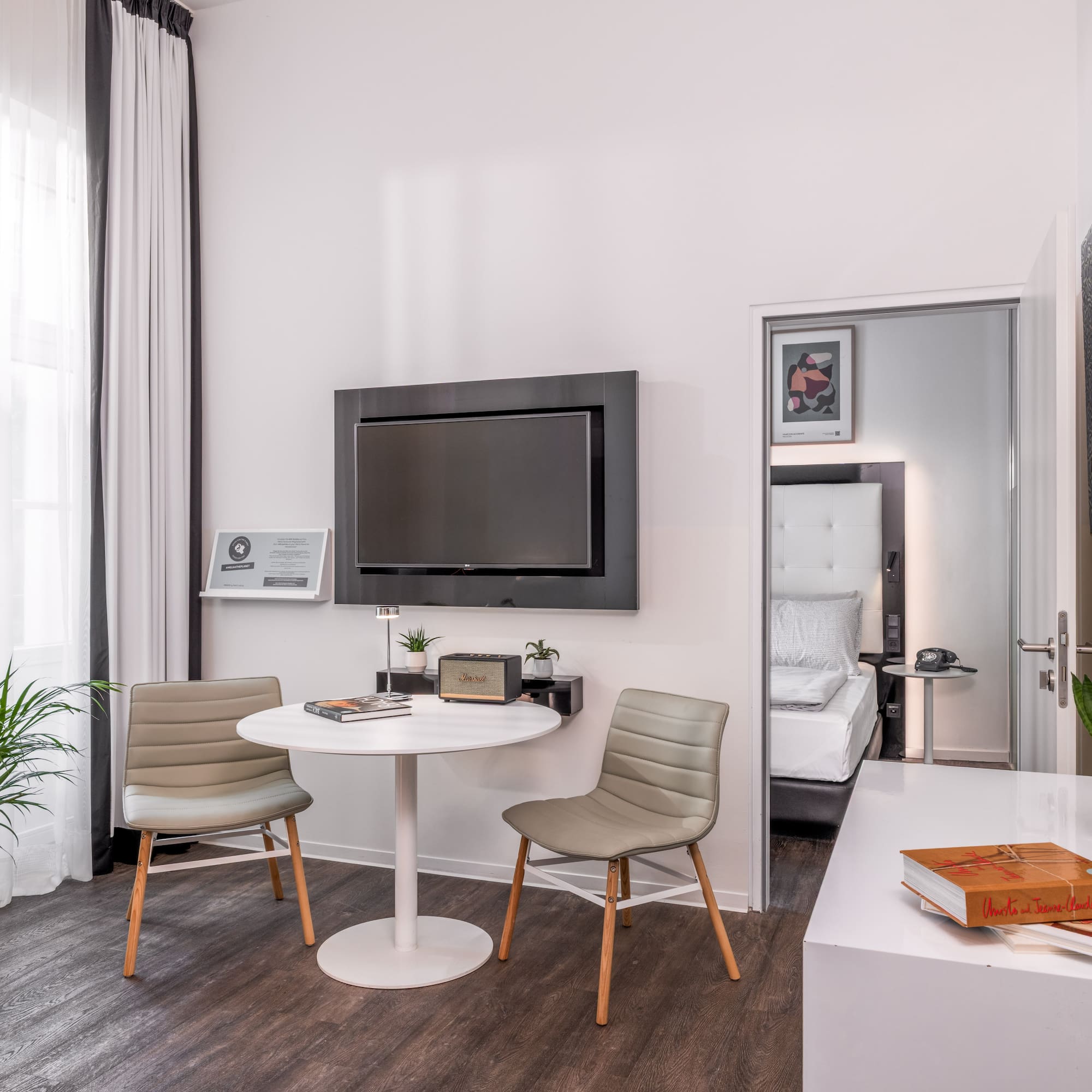 Stylish hotel room with contemporary decor, TV, small table, and bedroom access.