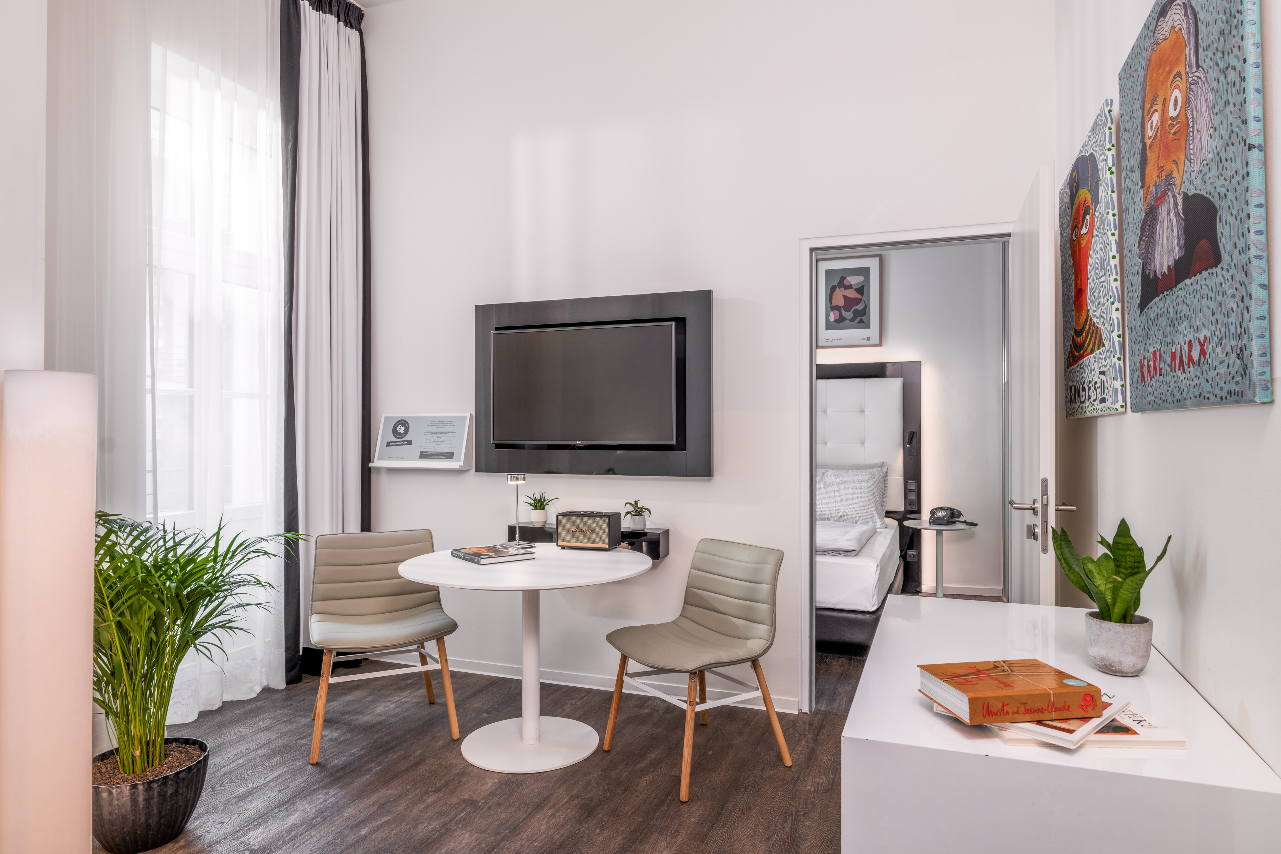 Stylish hotel room with contemporary decor, TV, small table, and bedroom access.