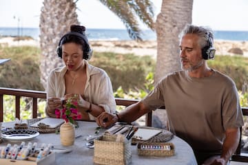 a man and woman sitting at a table with headphones