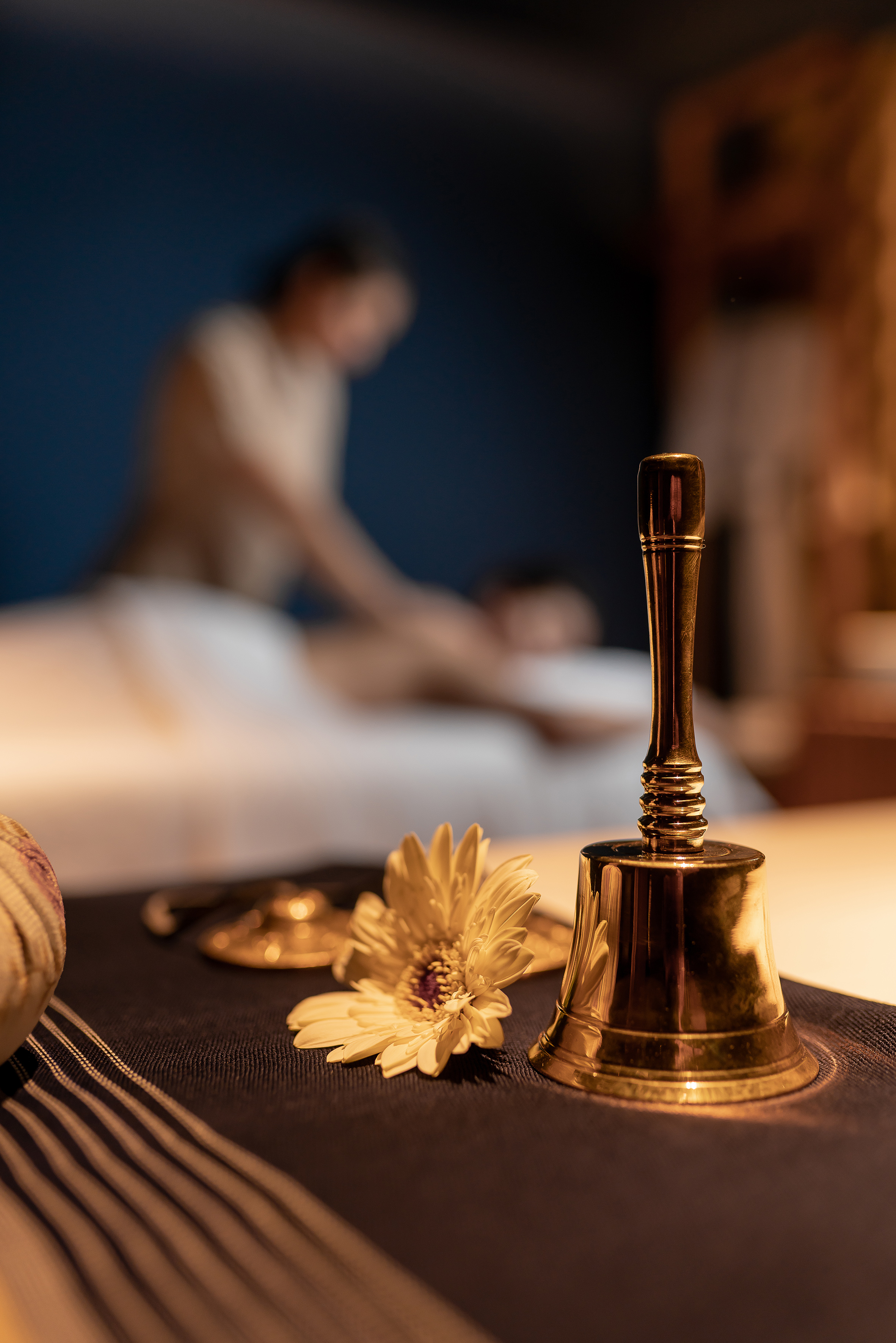 Golden bell, white flower, and blurred massage therapy session.