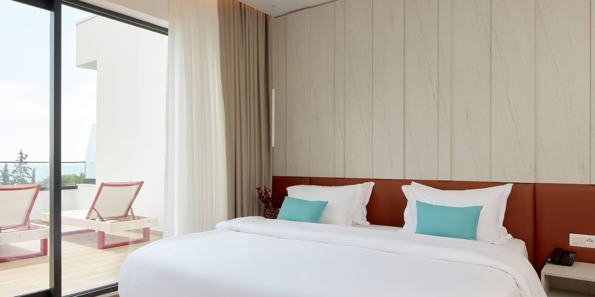 a bed with white sheets and blue pillows in a room with a glass door