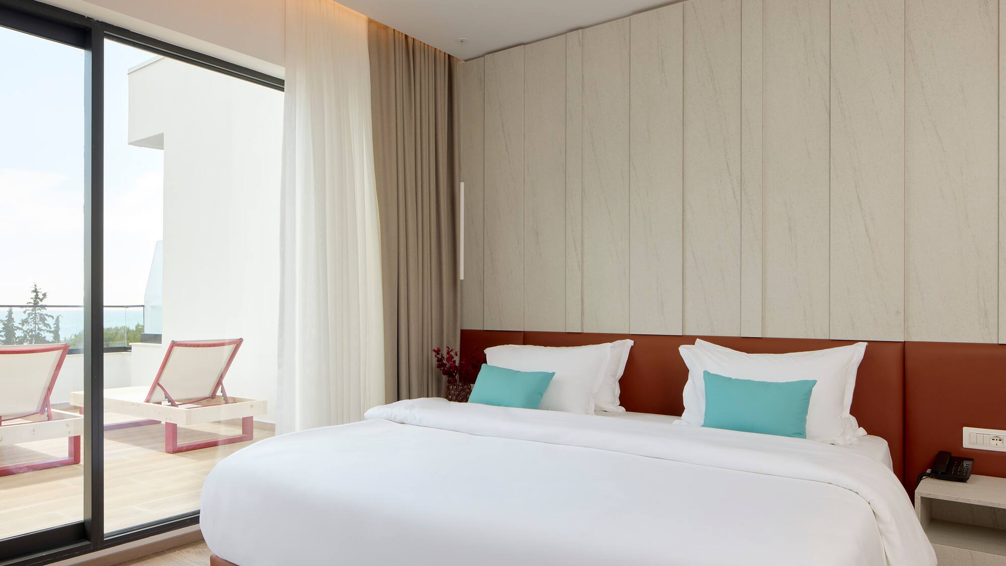 a bed with white sheets and blue pillows in a room with a glass door