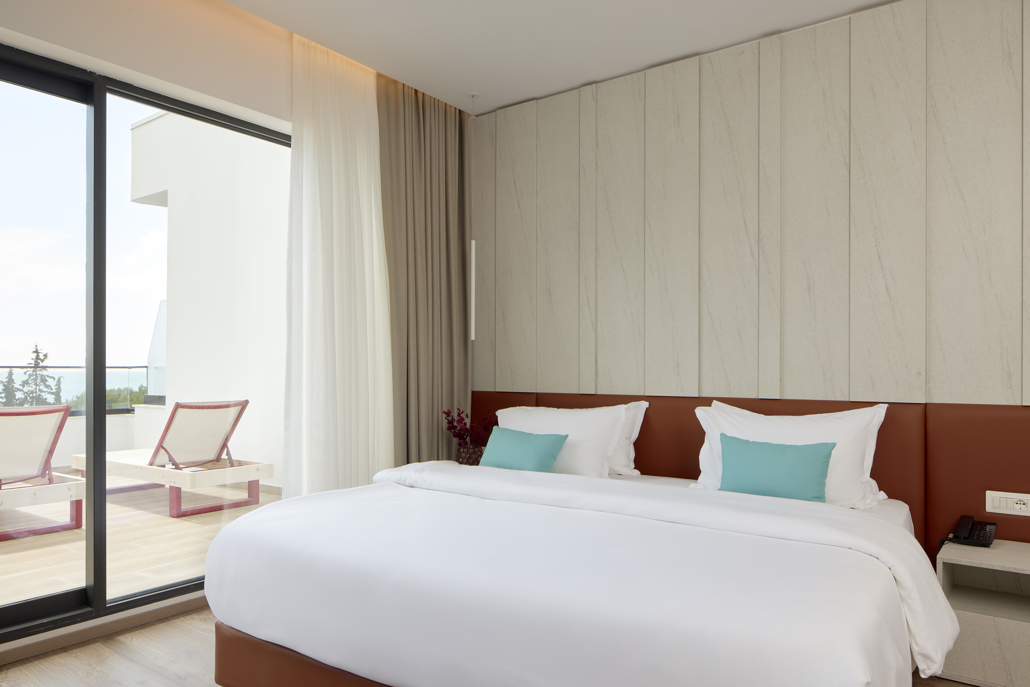 a bed with white sheets and blue pillows in a room with a glass door