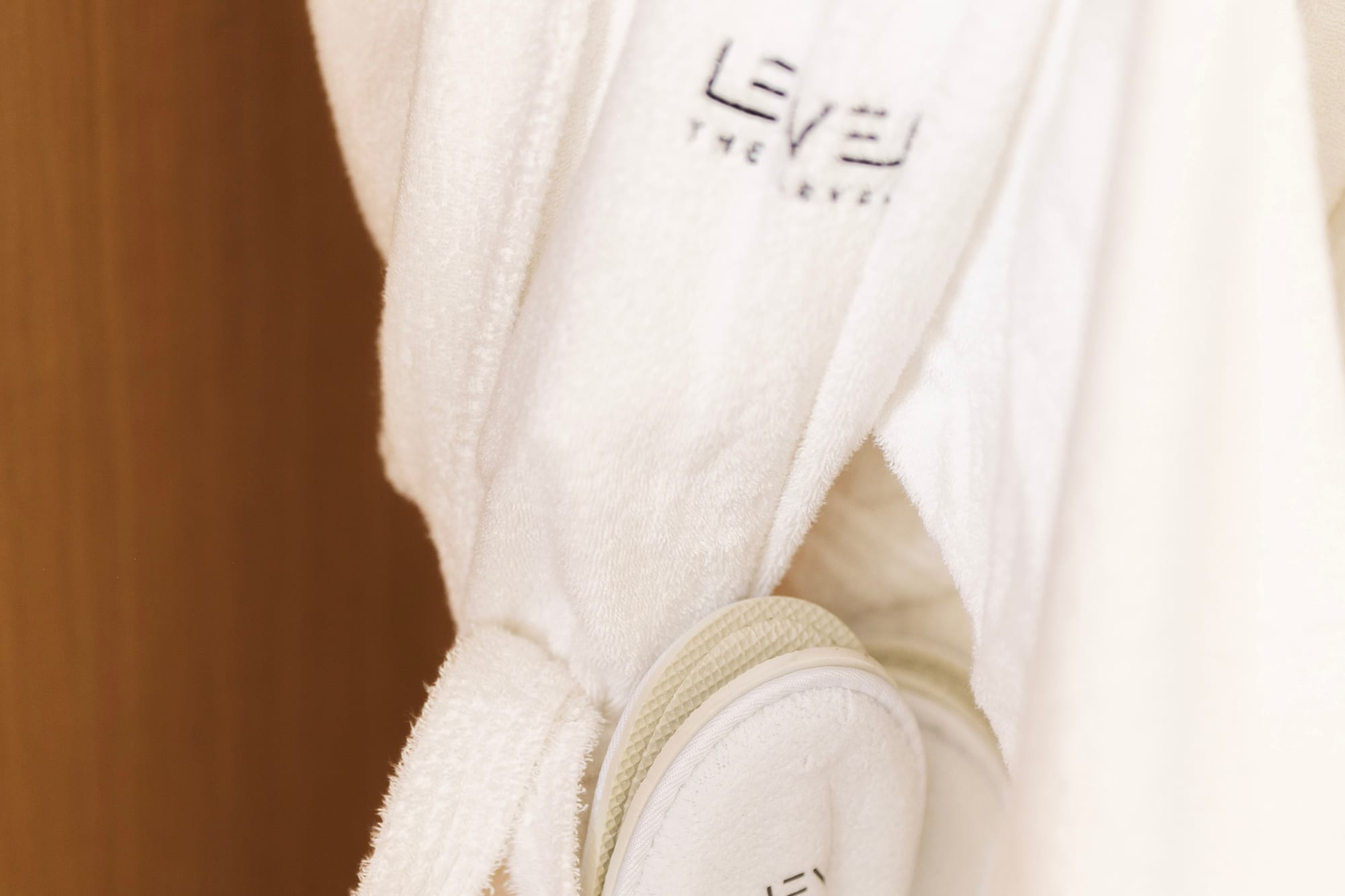 Plush white bathrobe and slippers with LEVEL logo luxury hotel amenities.