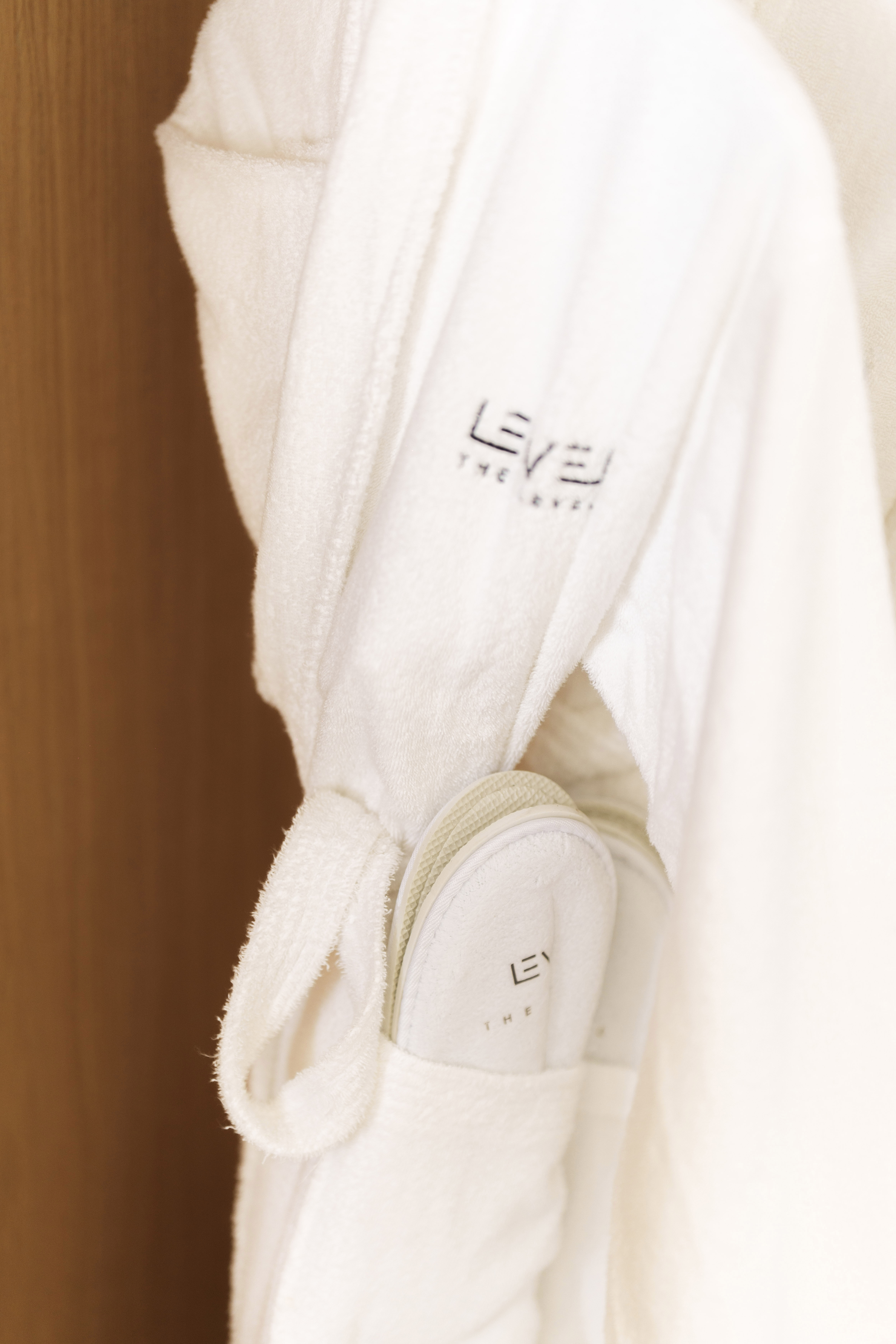 Plush white bathrobe and slippers with LEVEL logo luxury hotel amenities.
