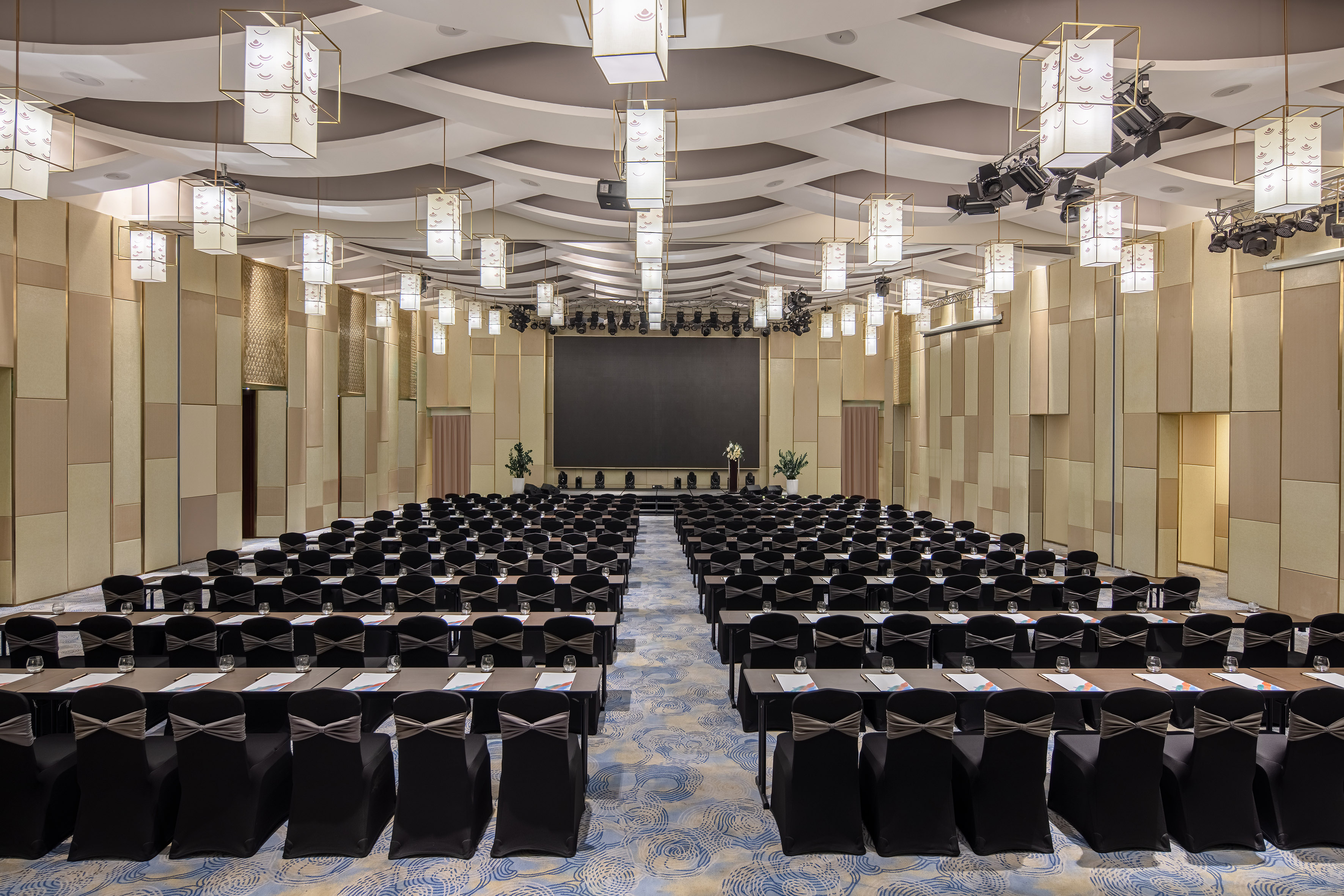 Elegant conference room with classroom setup, large screen, and stylish lighting.